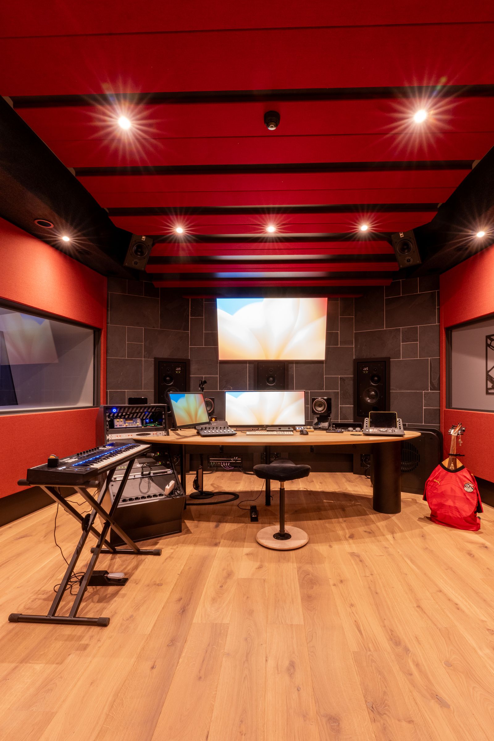 Studio van TFA met rode wanden, een houten regietafel, keyboard en studiomonitoren