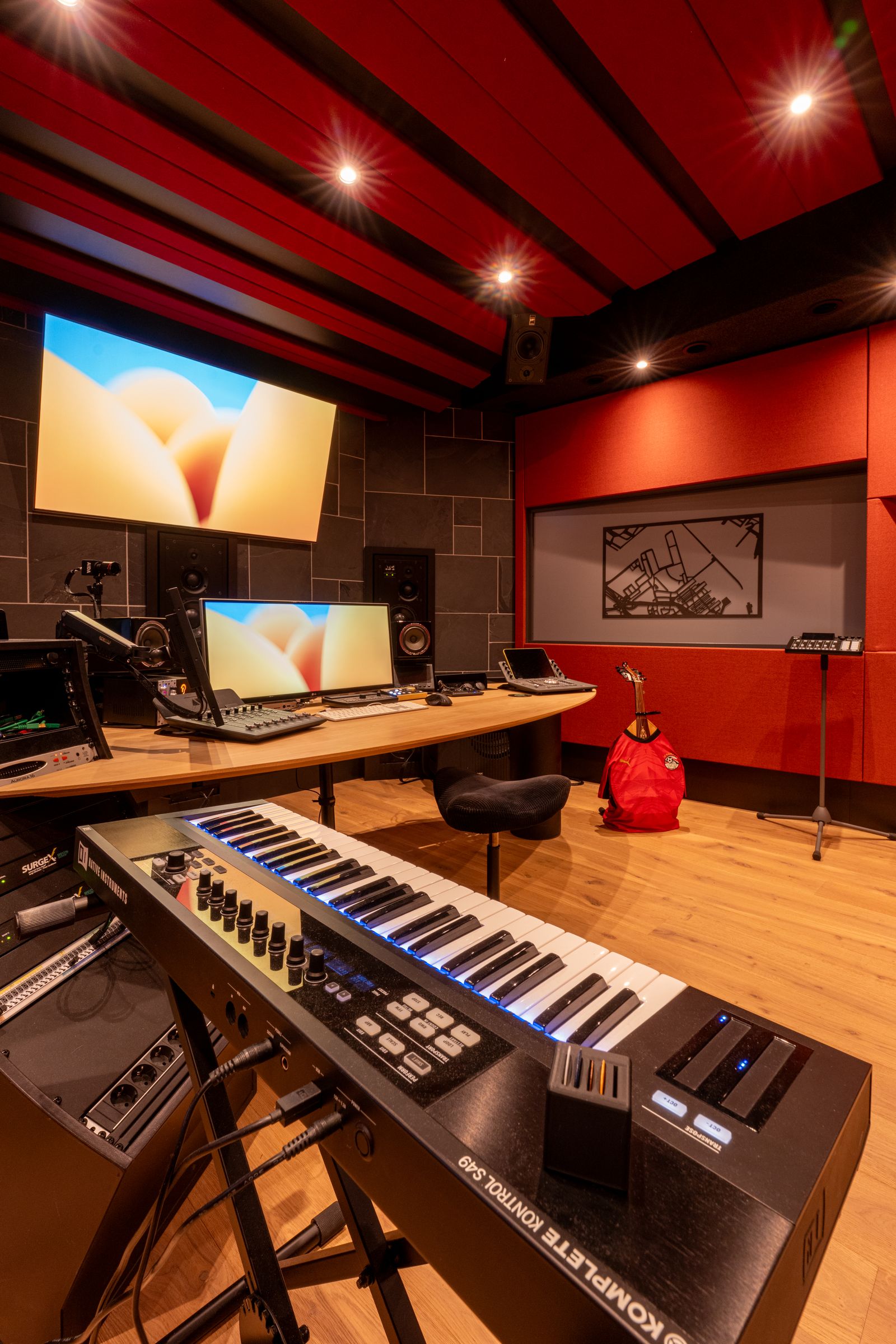 Studio van TFA met rode wanden, een houten regietafel, keyboard en studiomonitoren