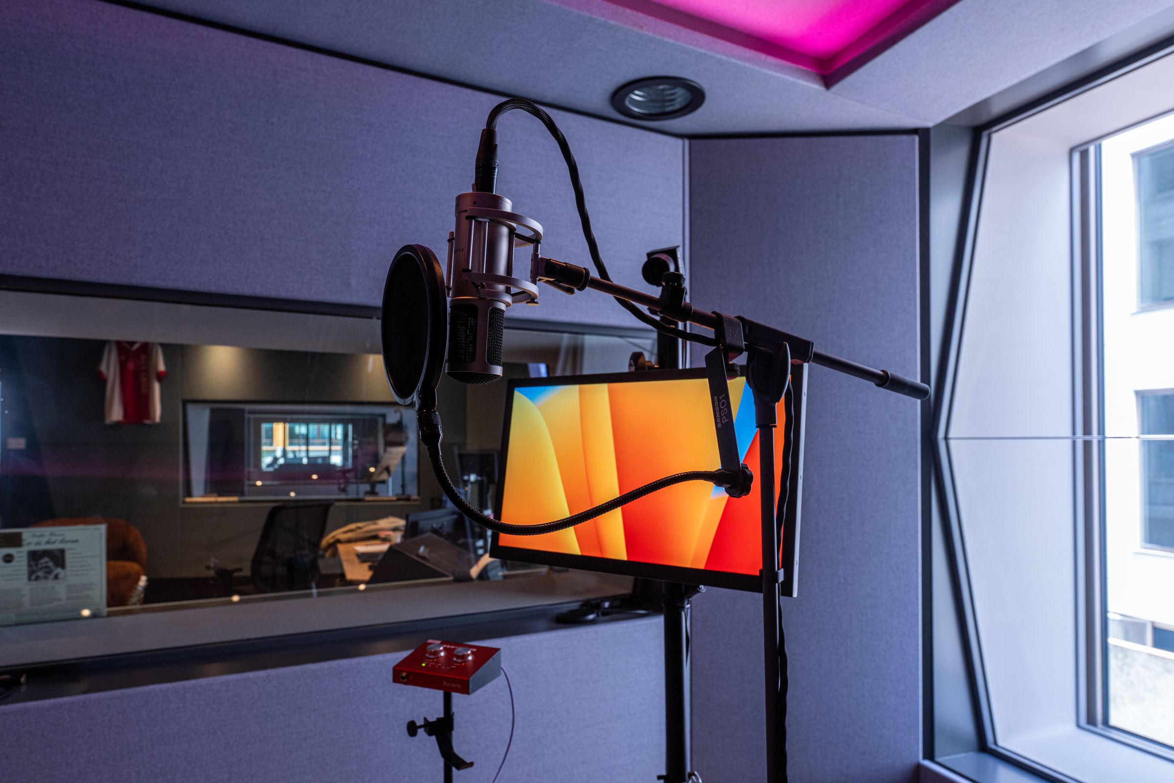 Studiomicrofoon met popfilter en tekstscherm in een opnamecabine van TFA