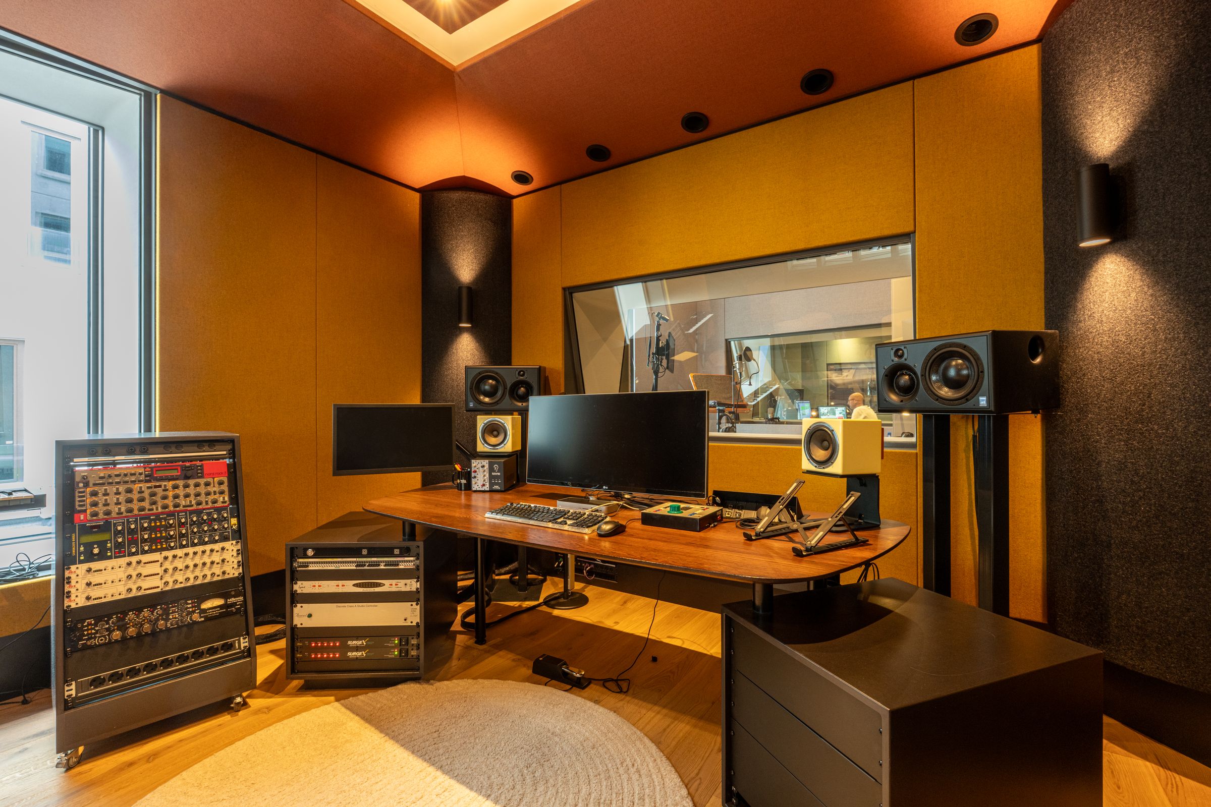 Studio van TFA met oranje en gele wanden, een regietafel, studiomonitoren en een rond tapijt