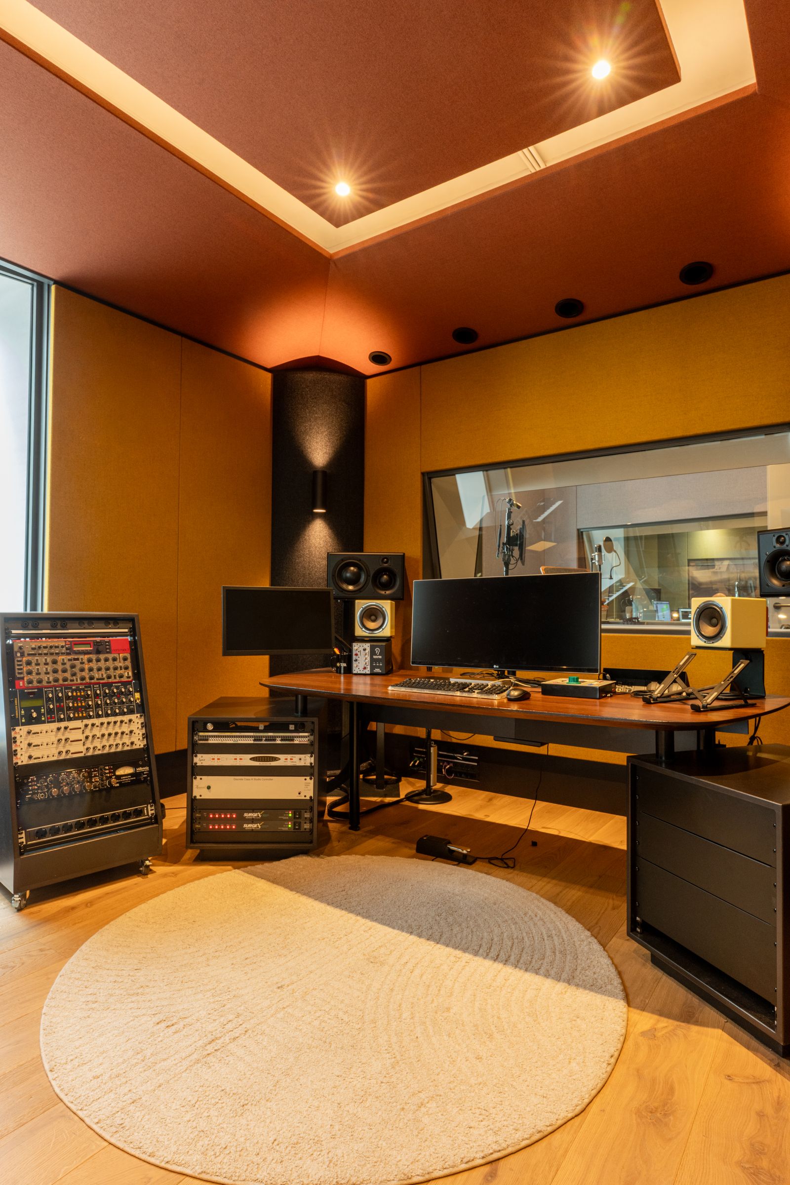 Studio van TFA met oranje en gele wanden, een regietafel, studiomonitoren en een rond tapijt