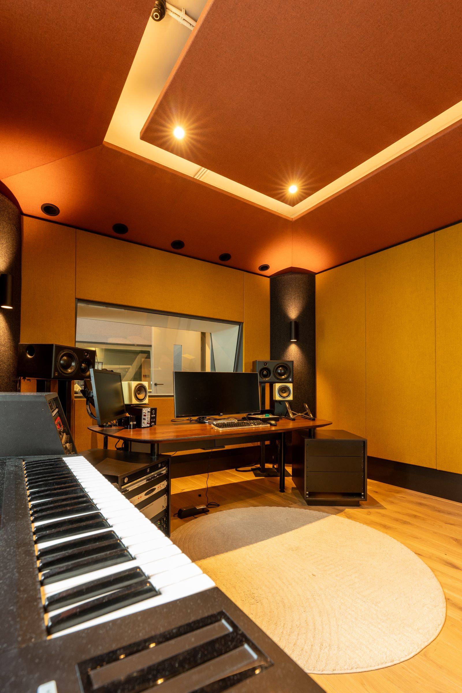 Studio van TFA met oranje en gele wanden, een regietafel, studiomonitoren en een rond tapijt