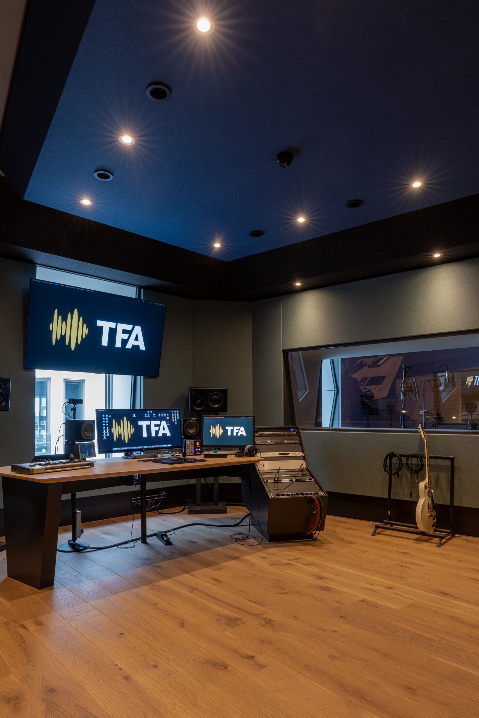 Studio van TFA met petrolblauwe wanden, een elektrische gitaar en het TFA-logo op het scherm