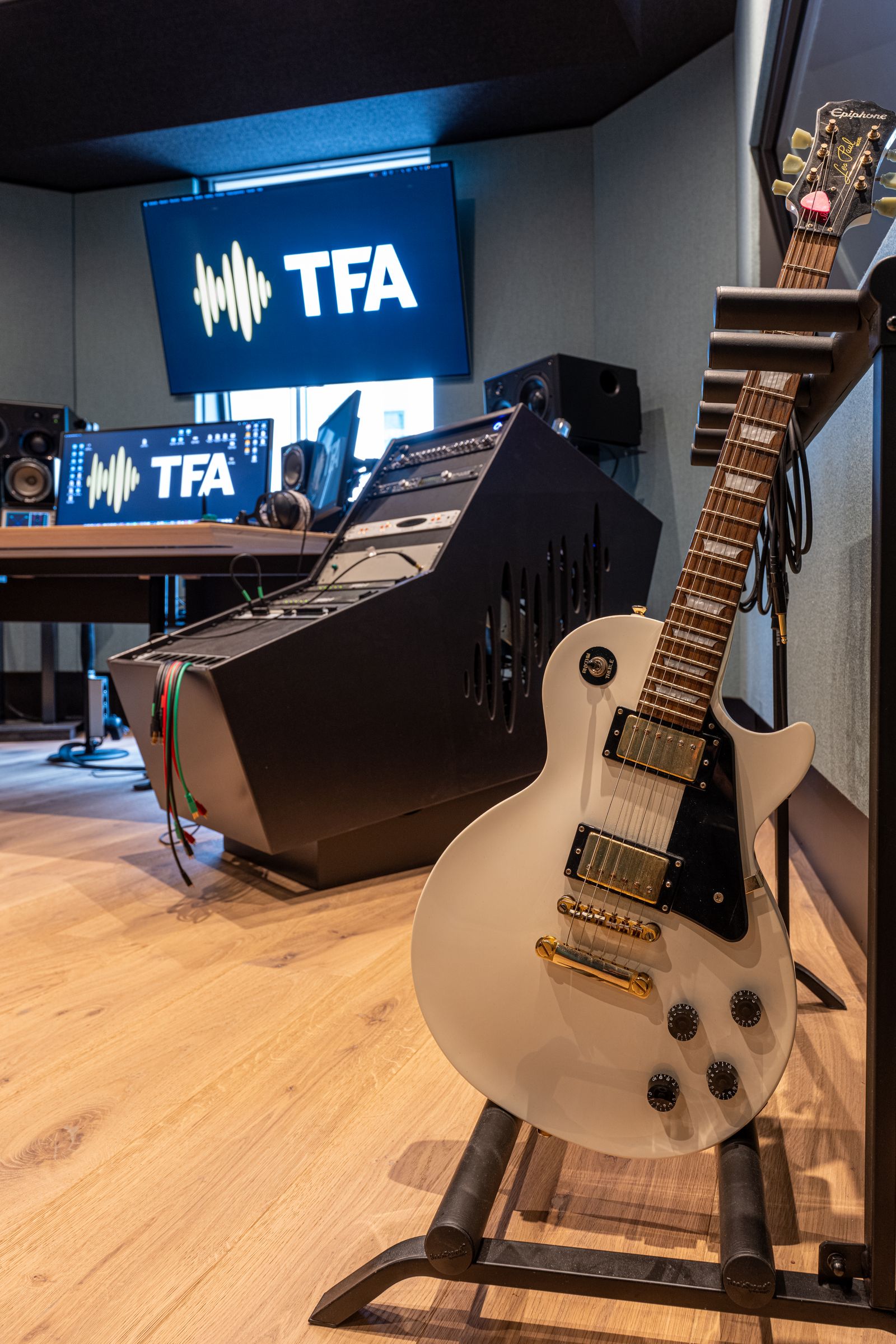 Studio van TFA met petrolblauwe wanden, een elektrische gitaar en het TFA-logo op het scherm