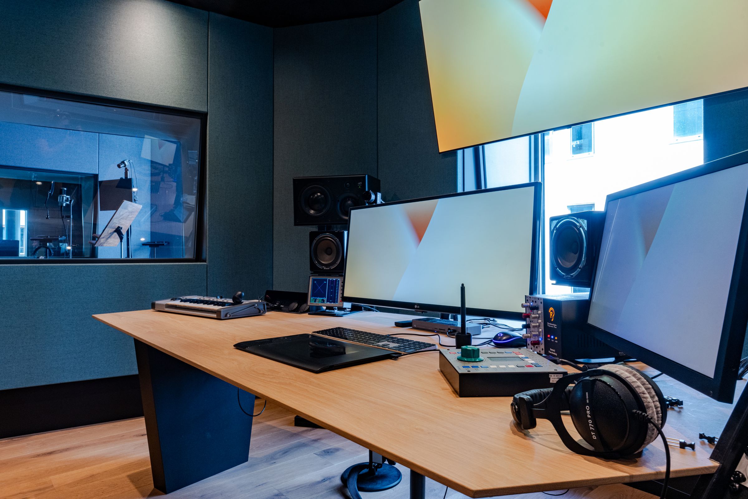 Bureau in een TFA-studio met schermen, koptelefoon en studiomonitoren
