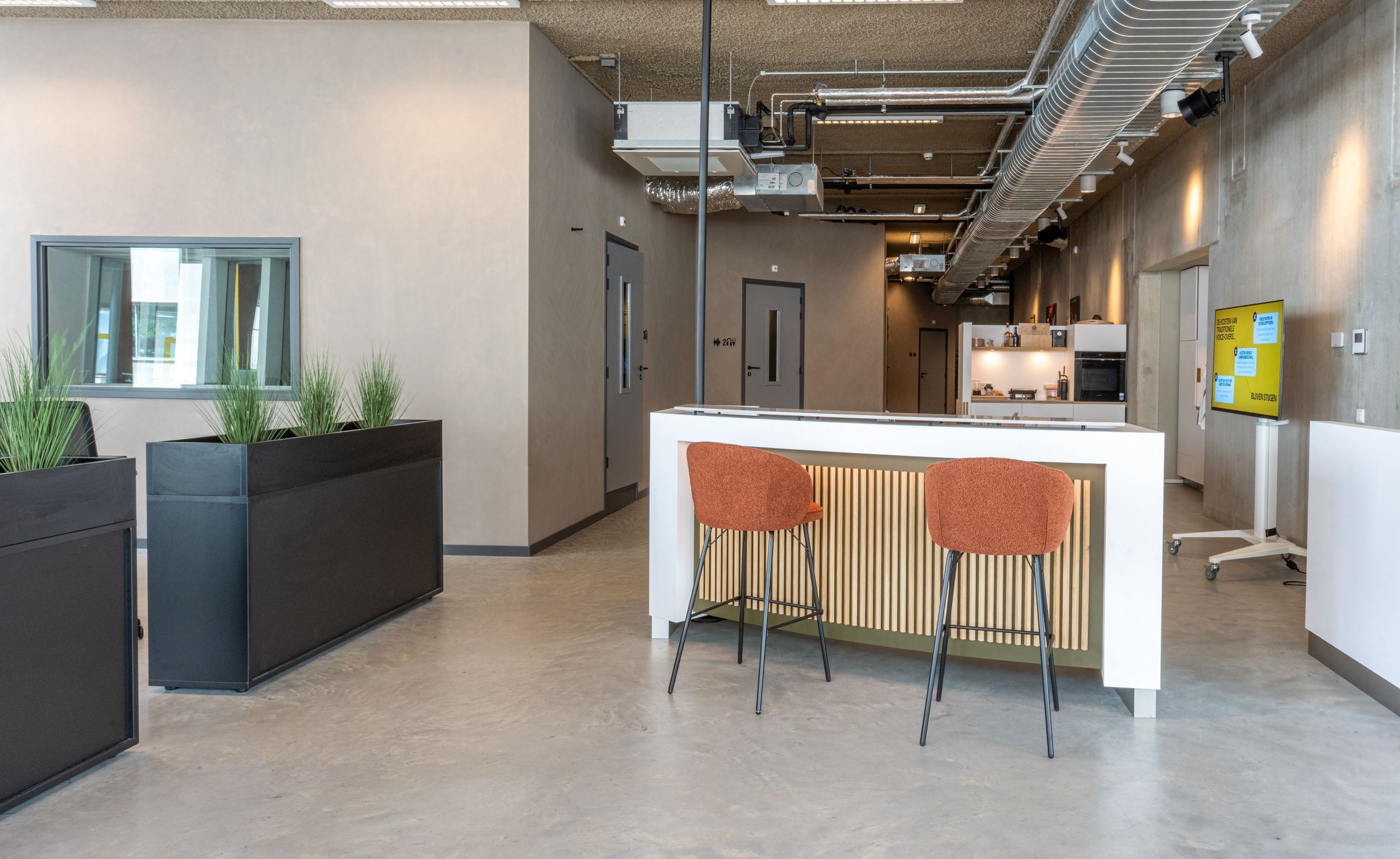Lichte lounge van TFA aan de Houthavens met een bar, barkrukken en planten