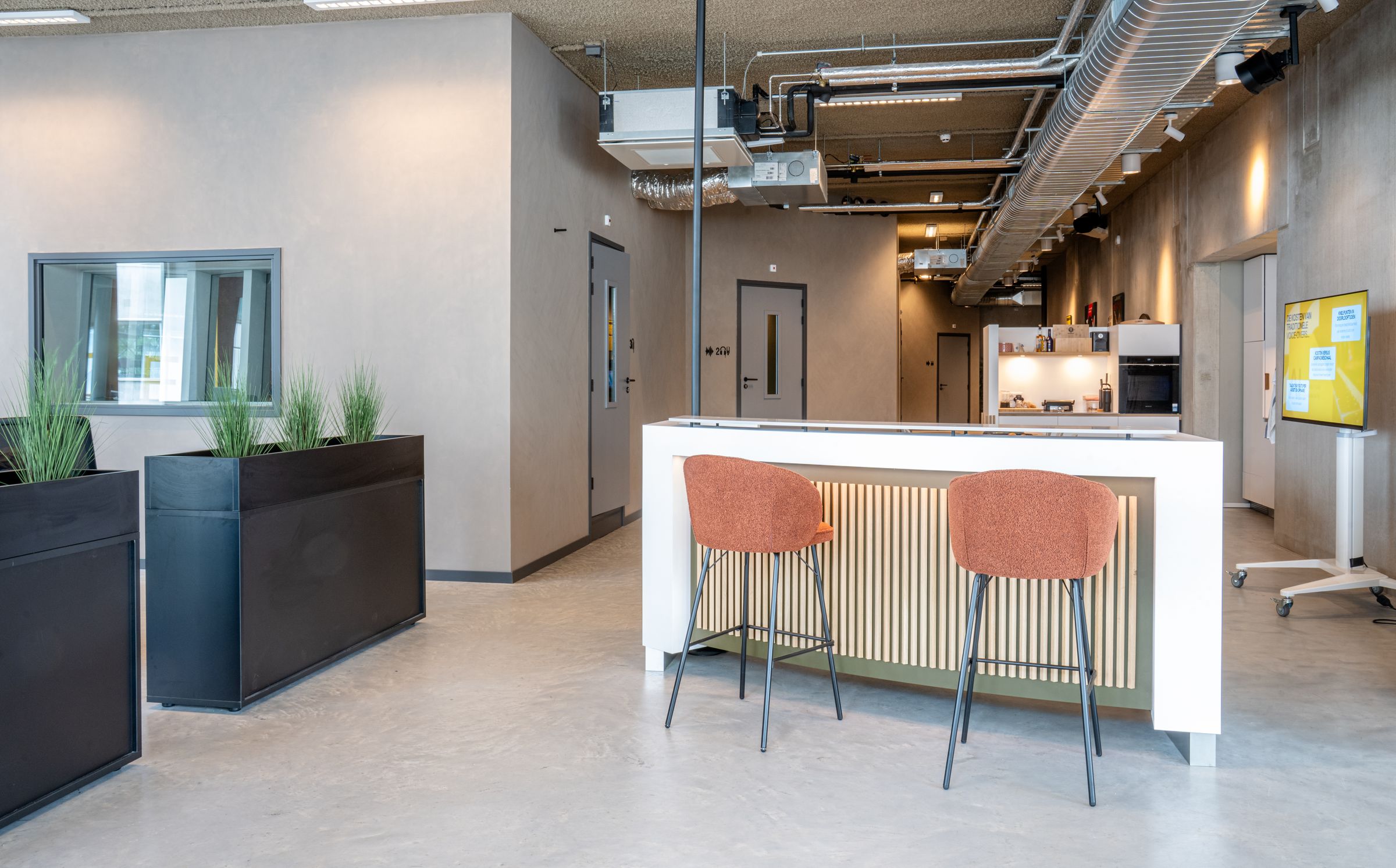 Lichte lounge van TFA aan de Houthavens met een bar, barkrukken en planten