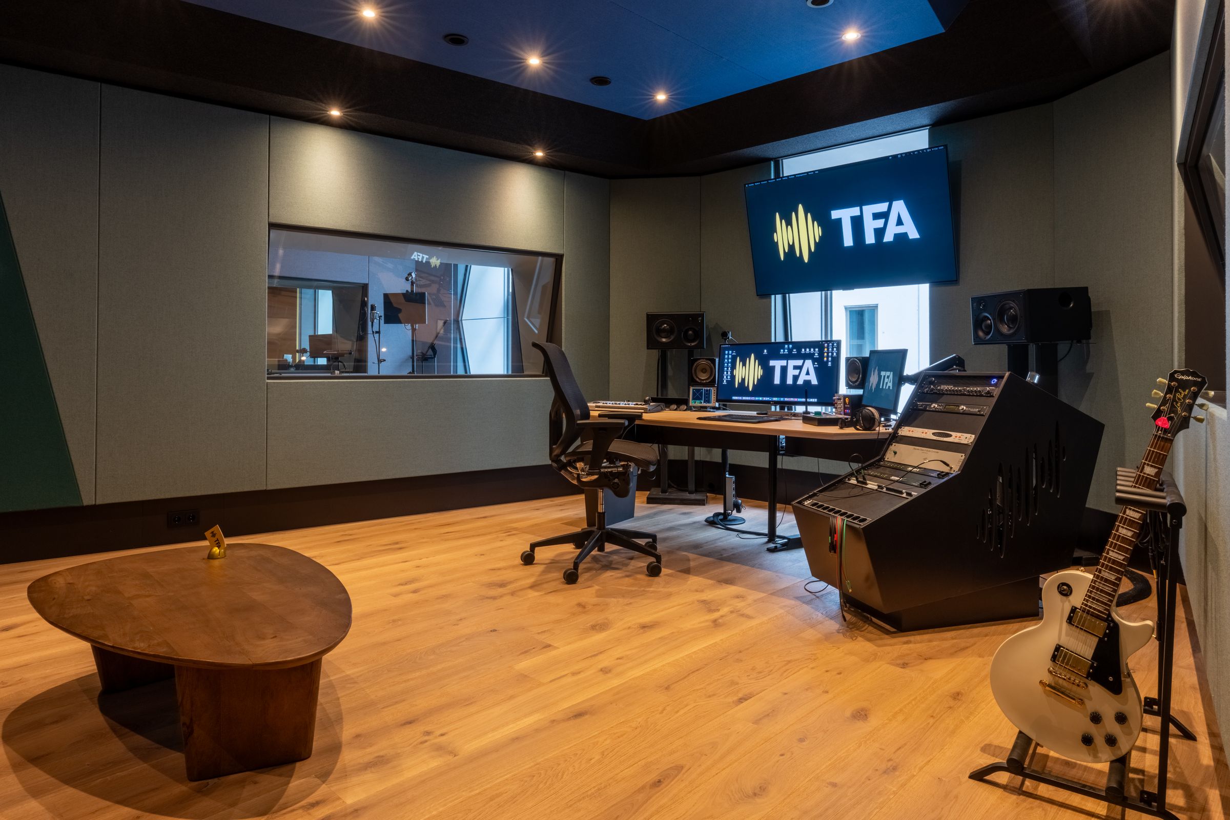 Regiekamer van TFA met mengtafel, studiomonitoren, gitaar en het TFA-logo op het scherm