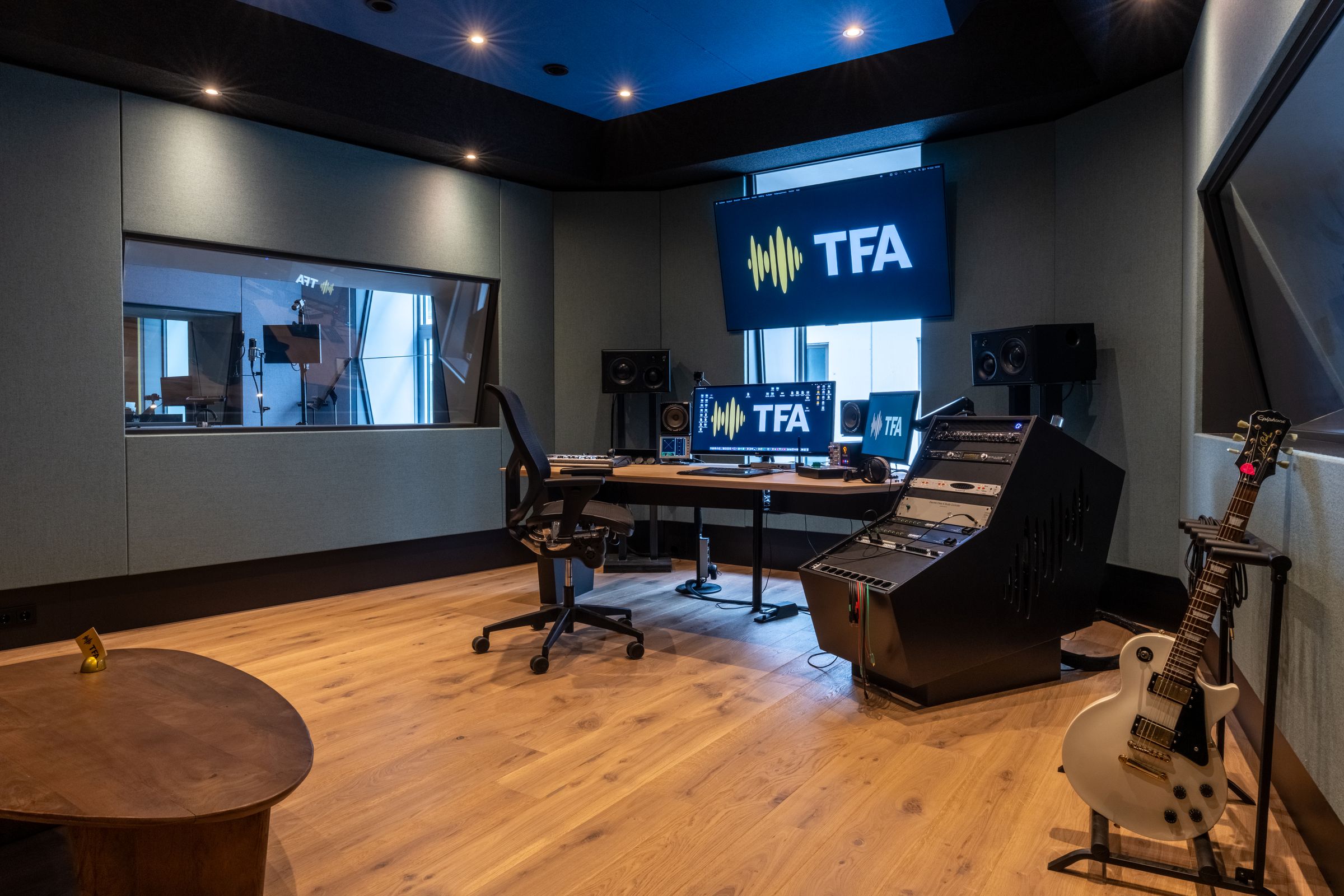 Regiekamer van TFA met mengtafel, studiomonitoren, gitaar en het TFA-logo op het scherm