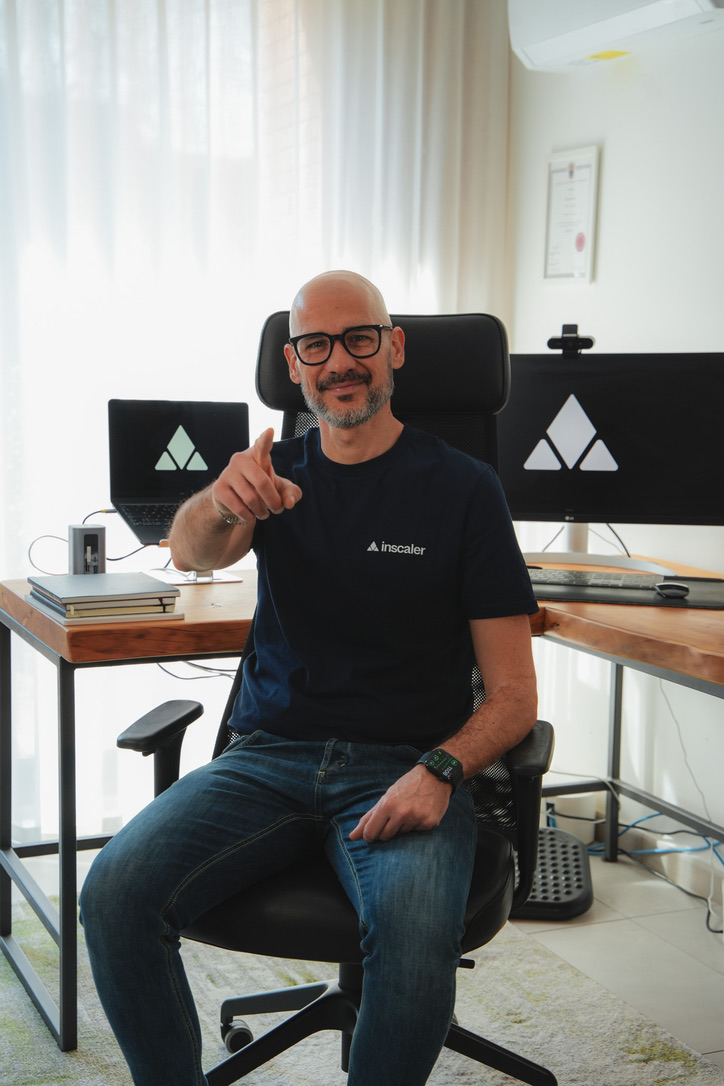 Matteo Papaluca, fondatore di Inscaler, seduto in ufficio con la maglietta Inscaler, indica verso la fotocamera