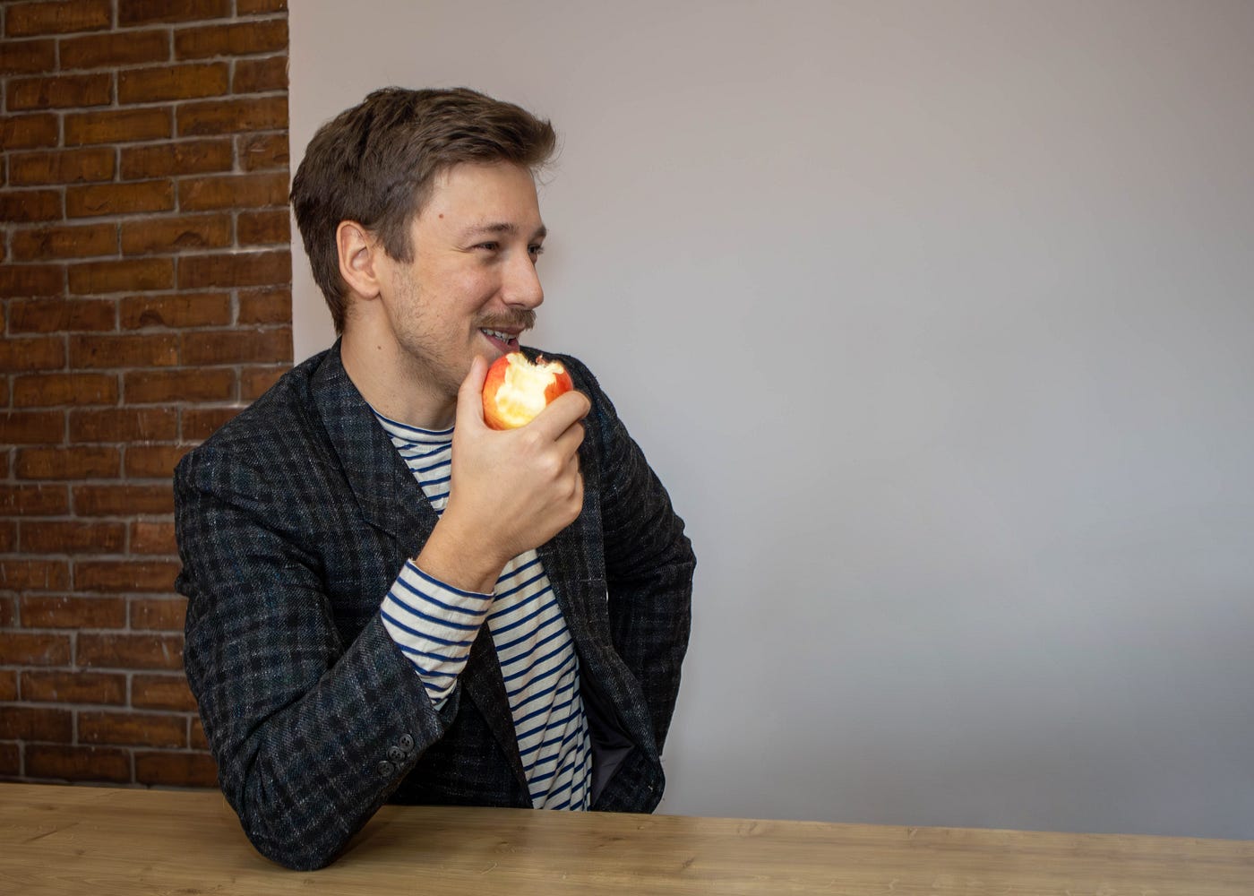 Man eating an apple at his office desk and smiling