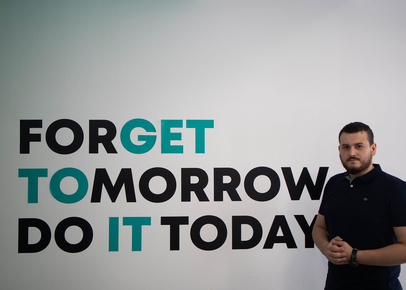 Intern standing in front of office logo for a workplace photo