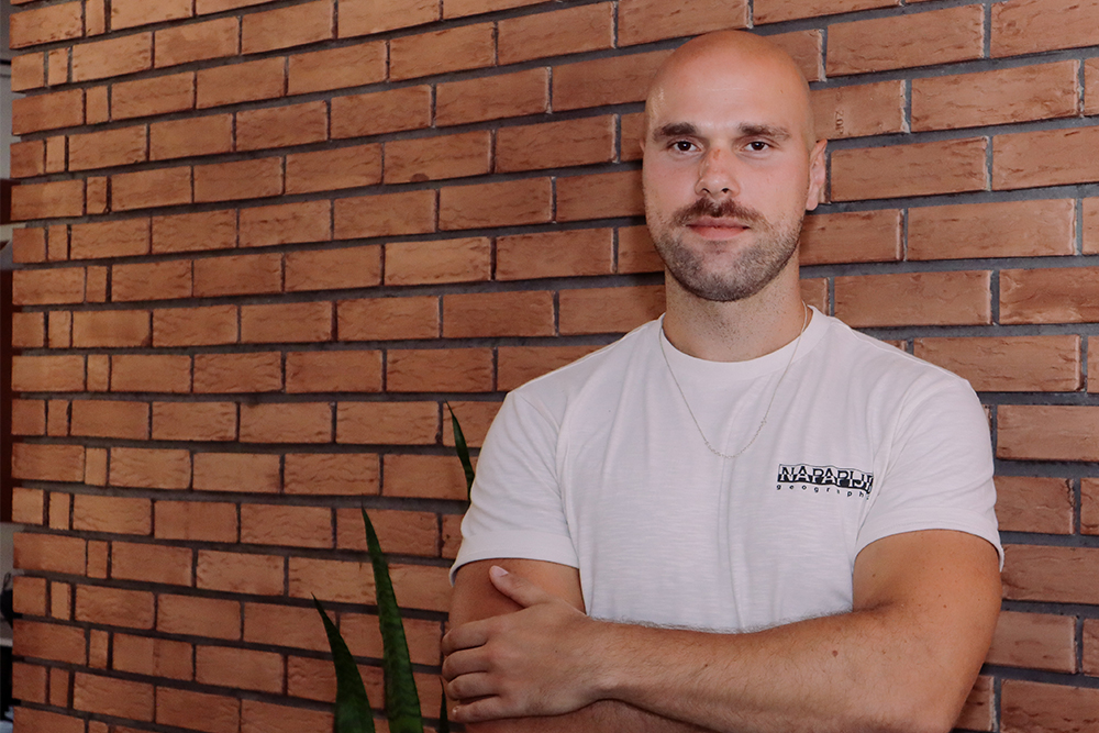 Professional posing for a portrait in front of textured brick wall