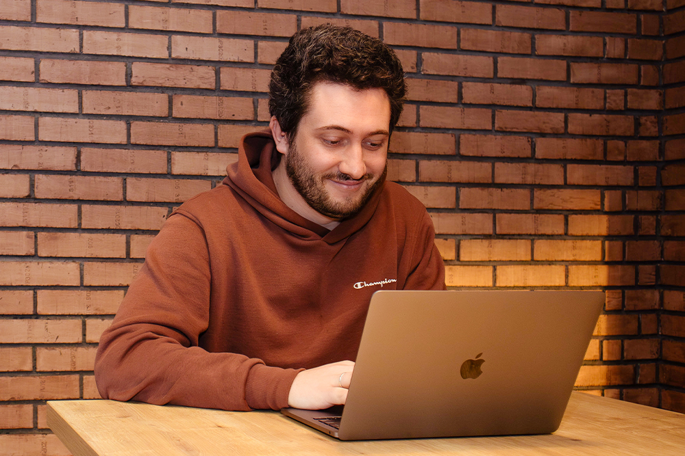 Man smiling while working on his laptop in the office