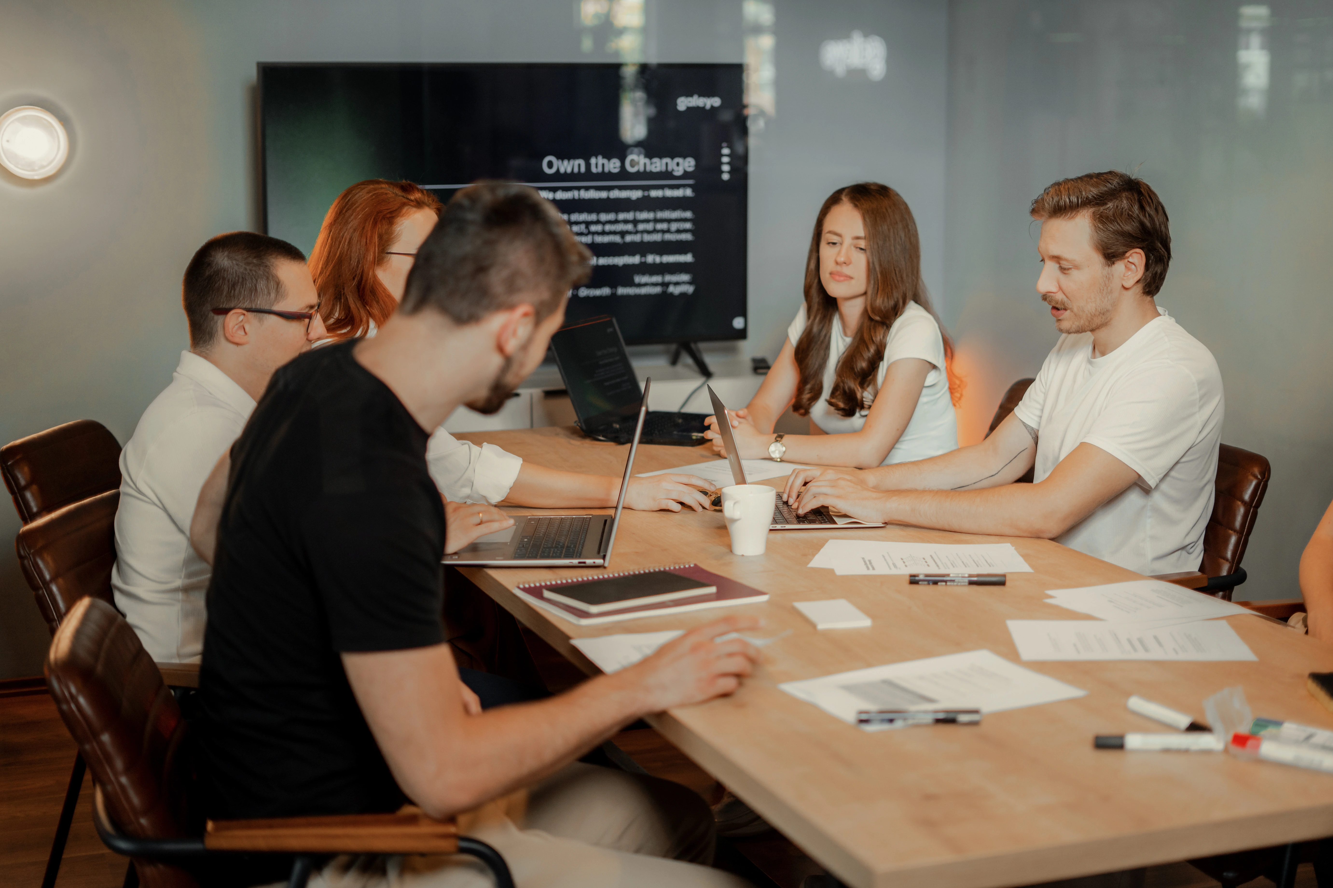 Galeyo team members in a relaxed discussion setting inside a modern glass meeting room