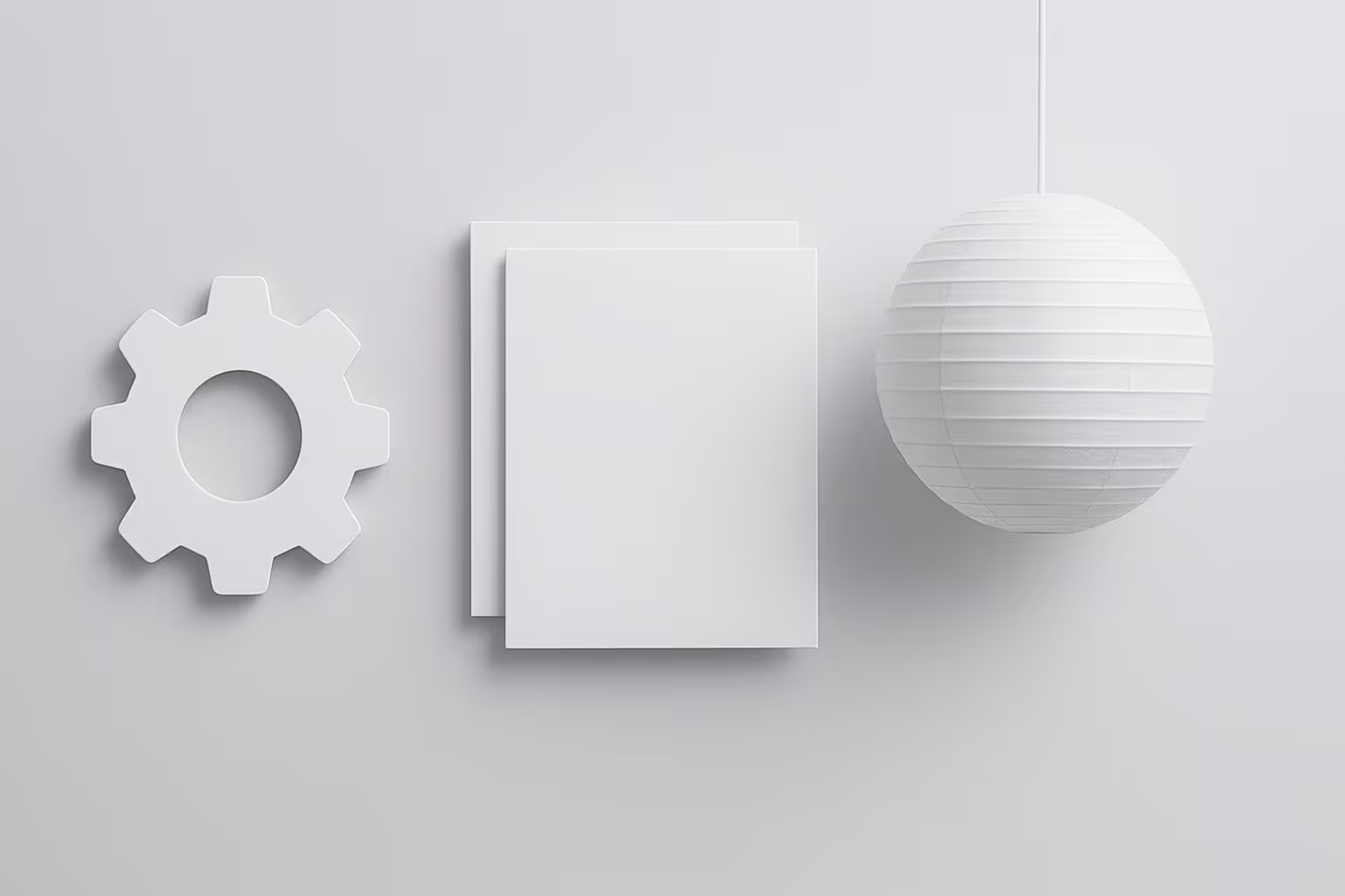 A white gear shape, two stacked rectangular sheets, and a round paper lantern hang against a plain light background.