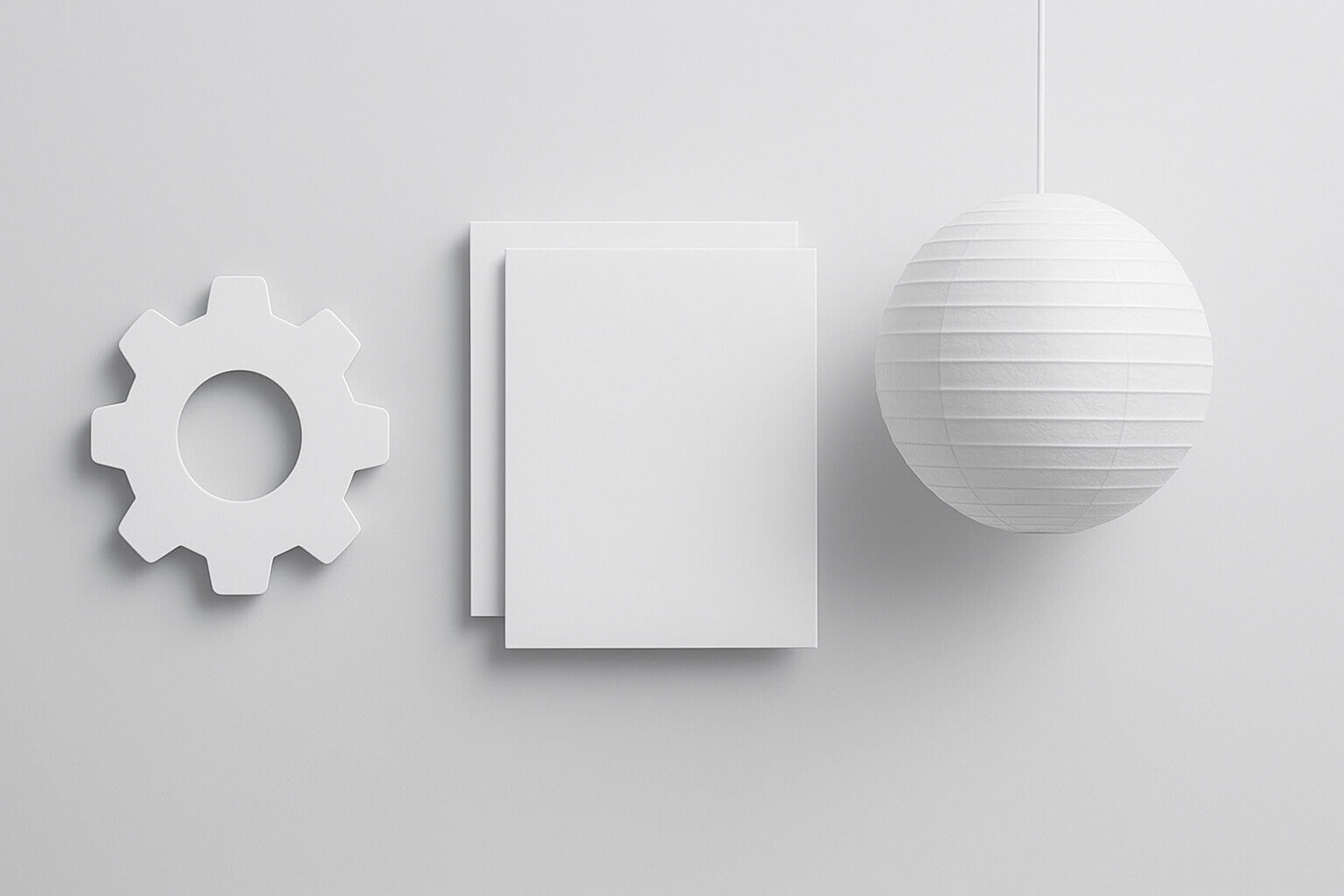 A white gear shape, two stacked rectangular sheets, and a round paper lantern hang against a plain light background.