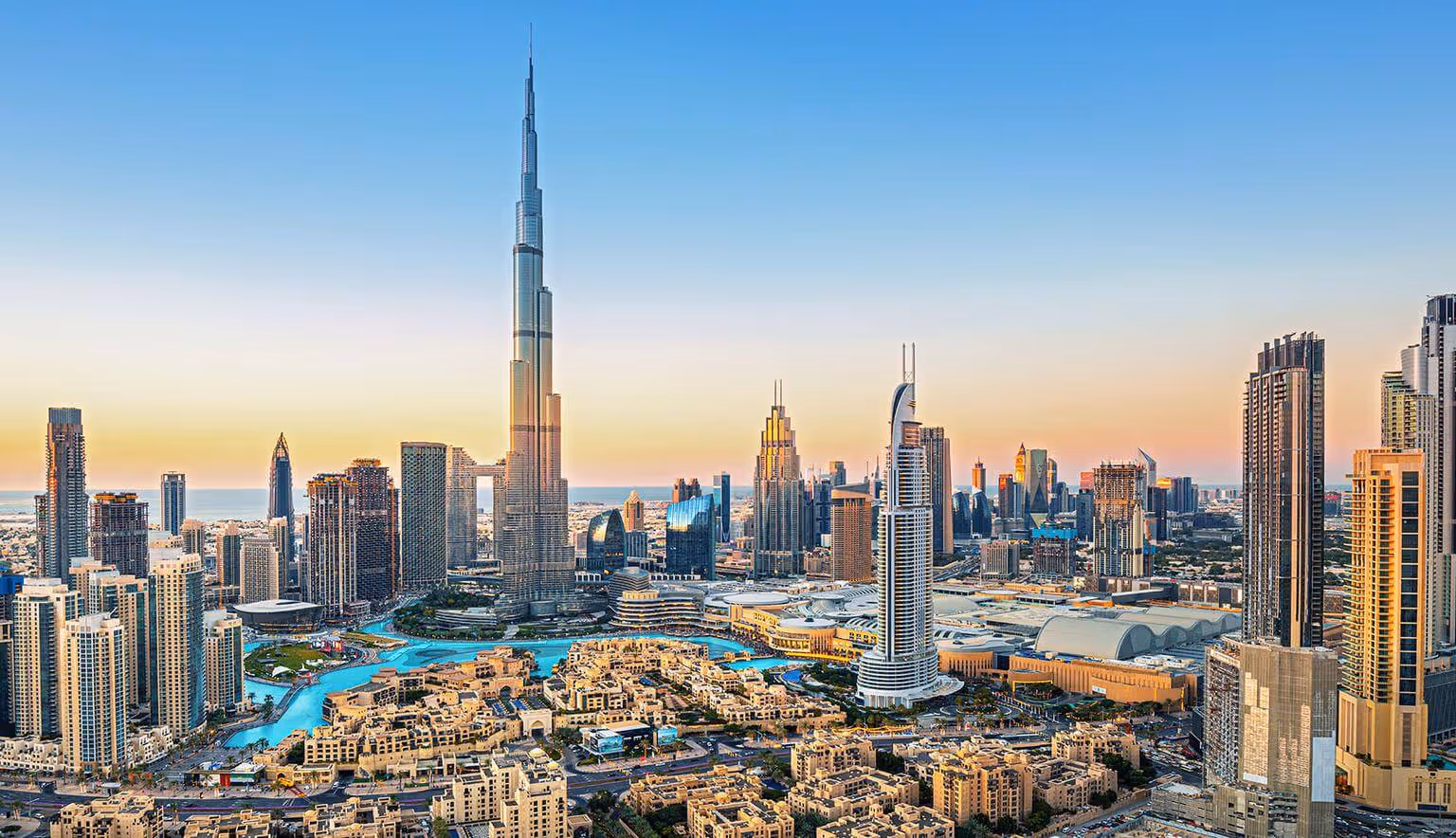 Tall modern skyscrapers and high-rise buildings under a clear blue sky during sunset.