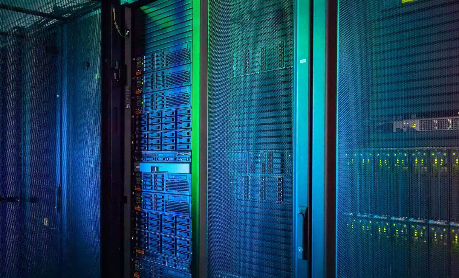 Server racks with multiple components and indicator lights are visible behind mesh doors in a room with blue-green lighting.