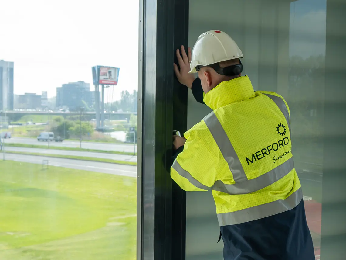 Merford employee opening a window with an acoustic grille installed behind it.