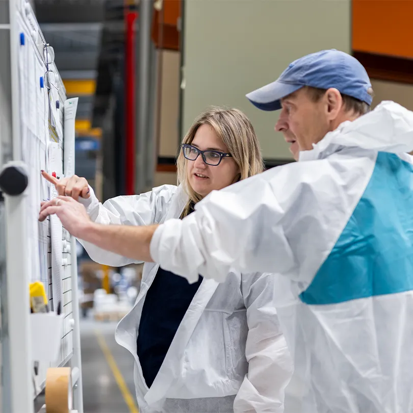 Two Merford production employees reviewing technical drawings on a whiteboard inside the factory.