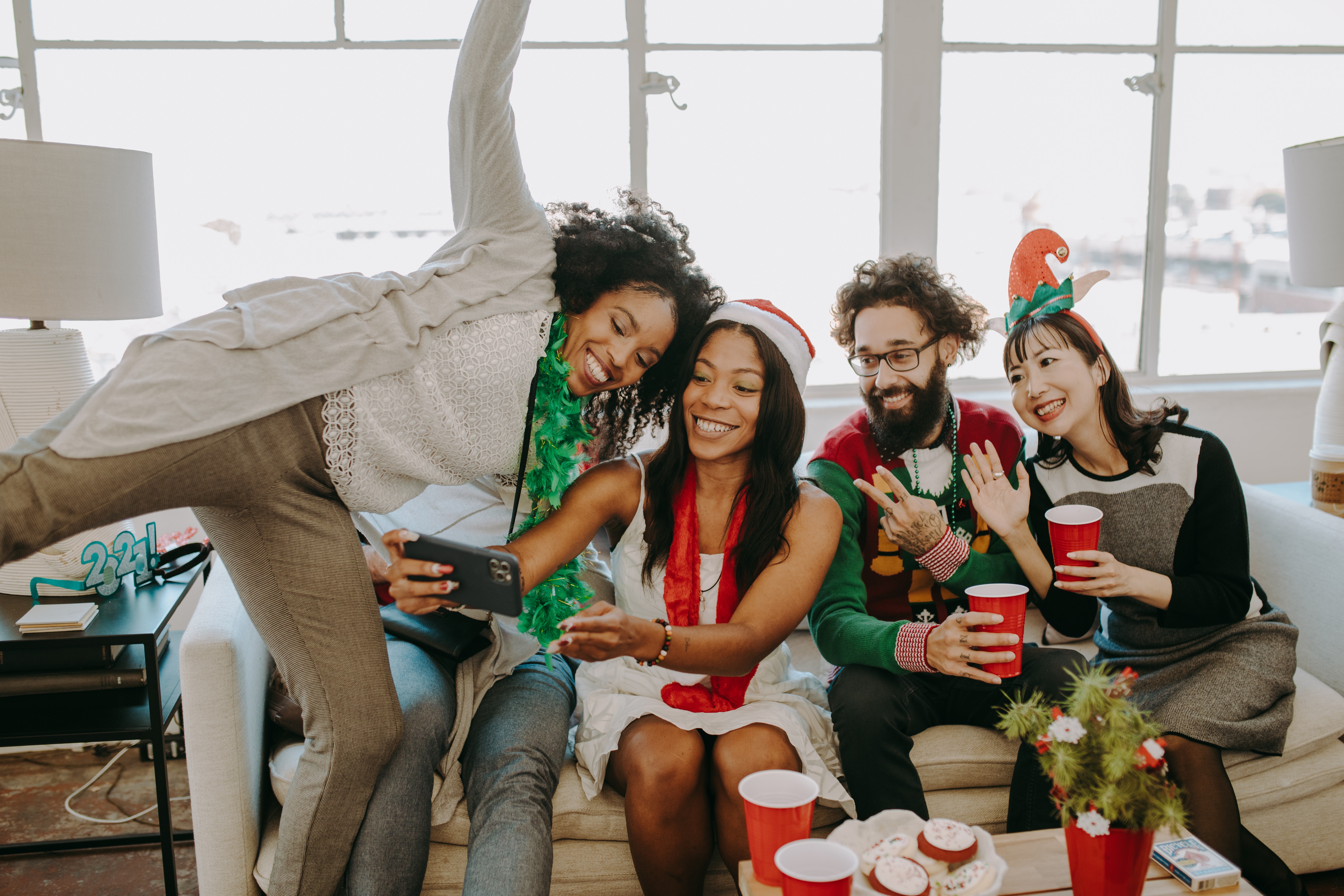 friends celebrating Christmas together, sitting on a couch and taking a selfie
