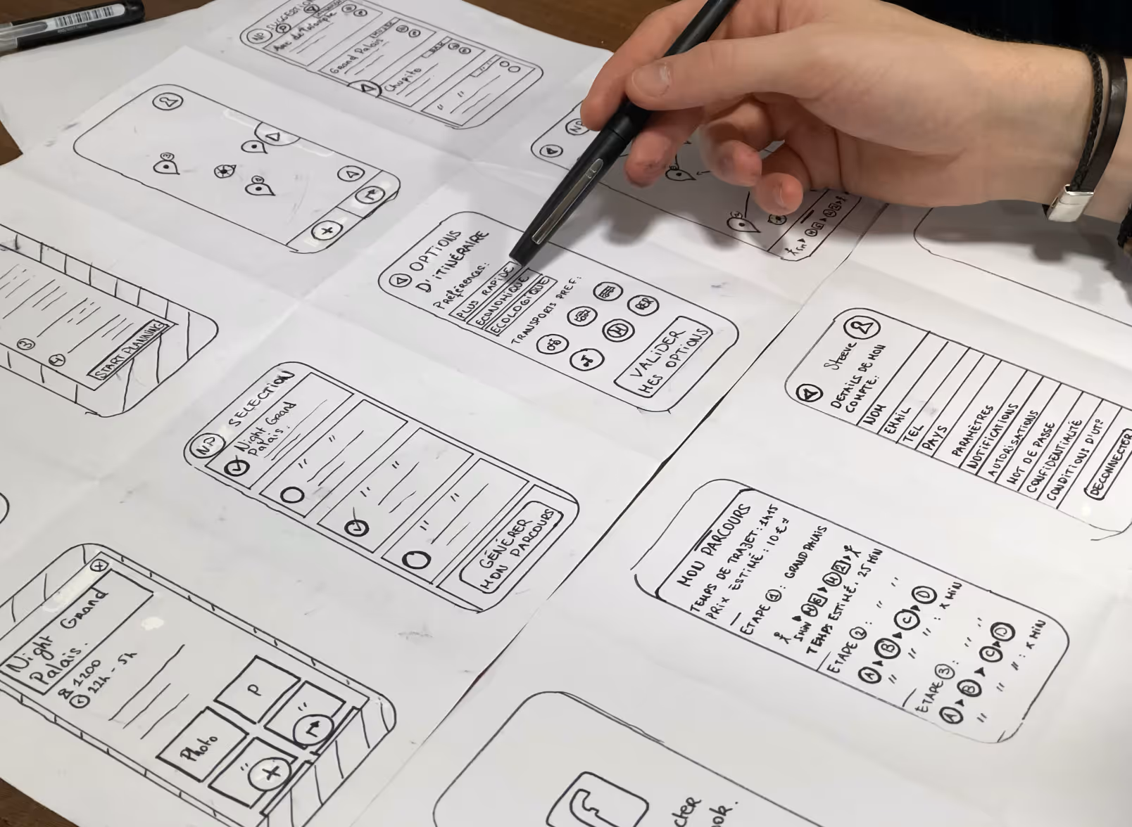 Hand sketching mobile app interface designs with a marker on paper