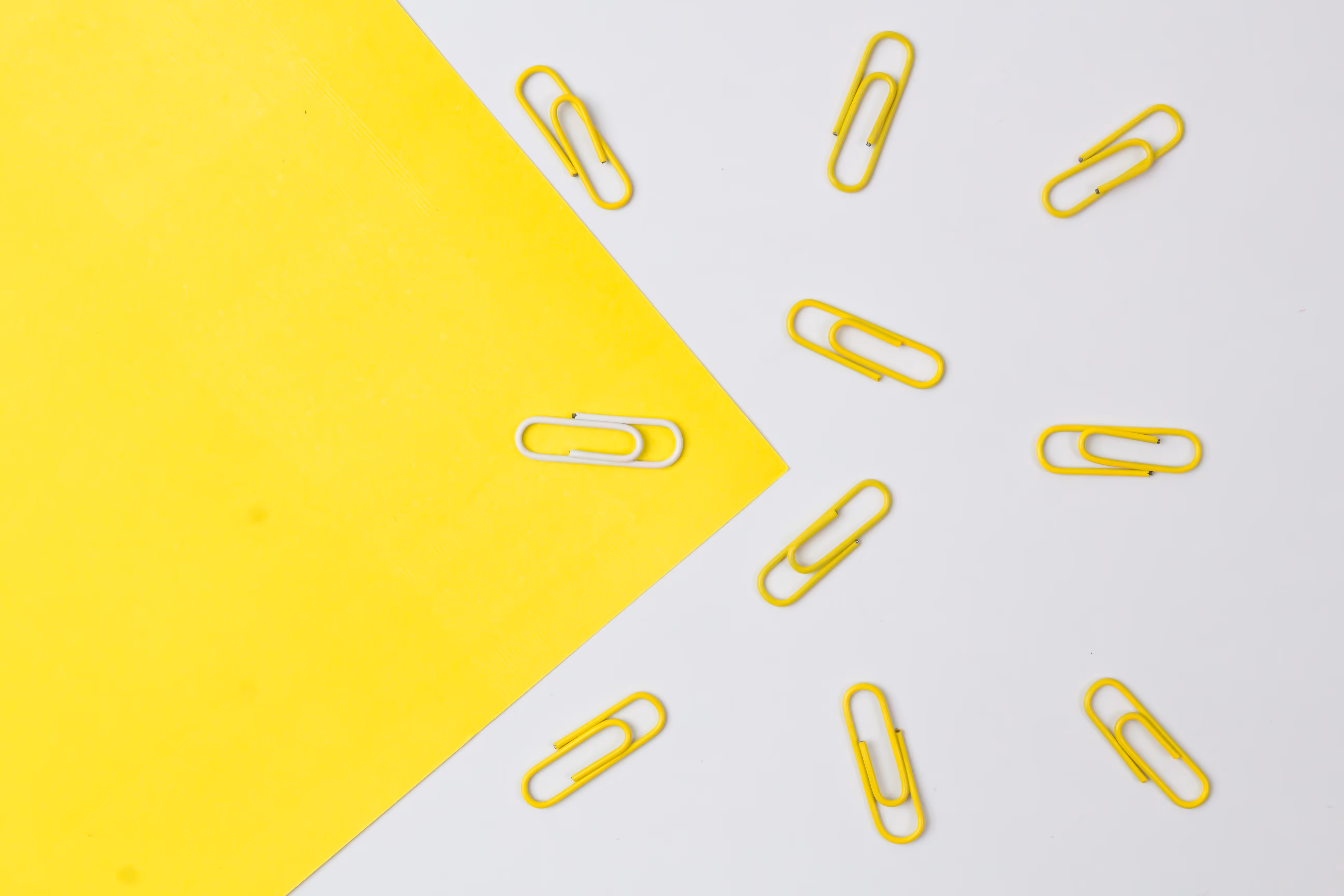 Yellow paper clips arranged around a yellow piece of paper showcasing product market