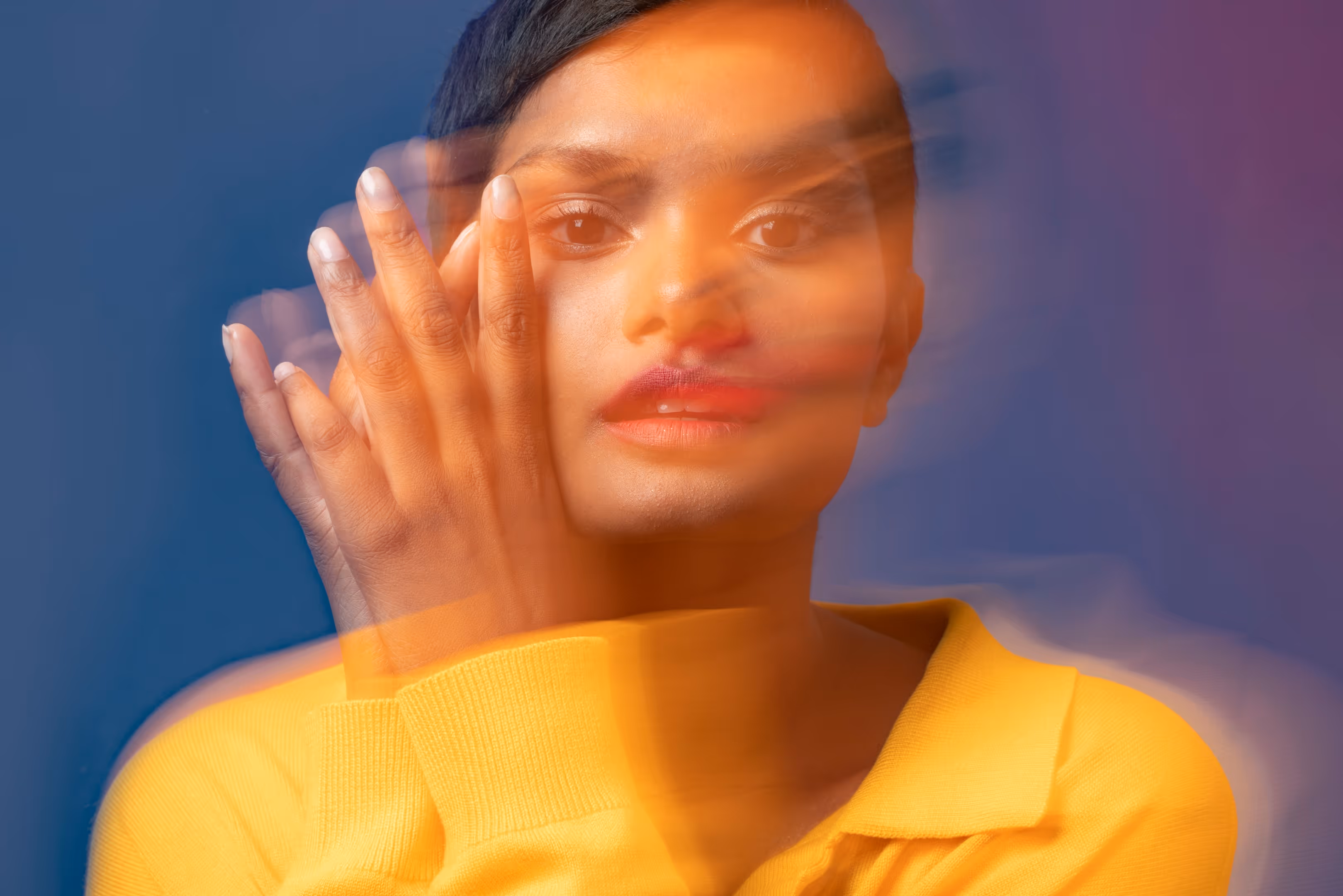 woman in yellow dress hand in face motion blur