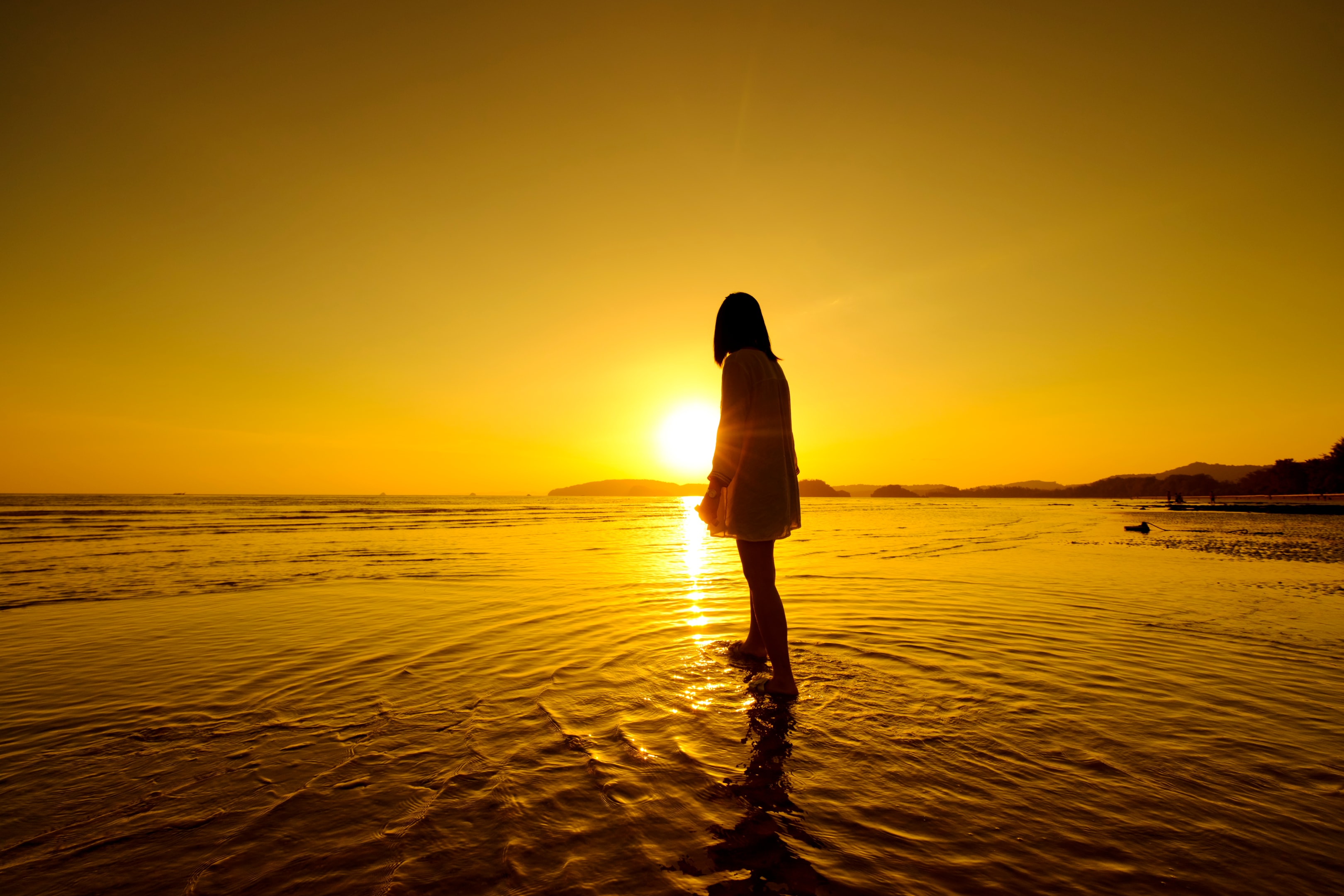 woman stnading on beach looking at sunset