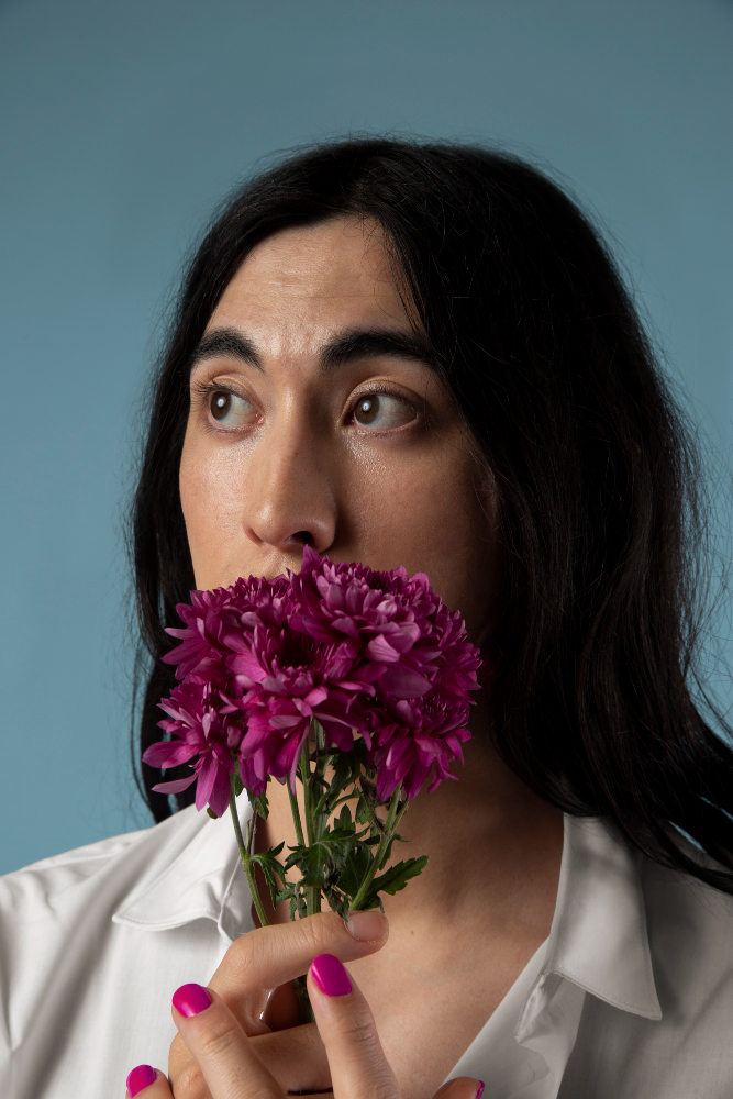 portrait photo of woman holding flower in front of mouth