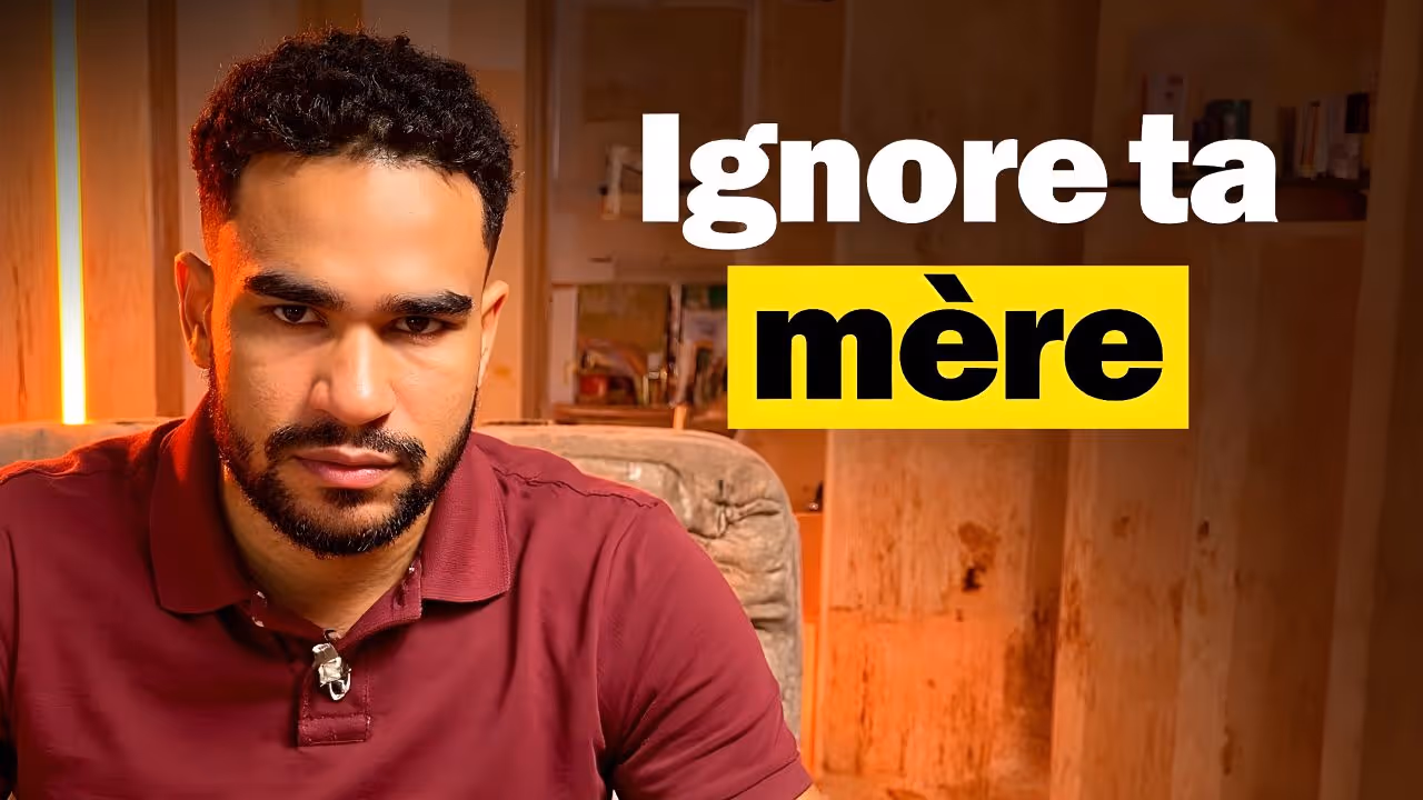 Homme au regard intense vêtu d’un polo bordeaux, assis dans un décor chaud et minimaliste, avec le texte “Ignore ta mère” en blanc et noir sur fond jaune vif.