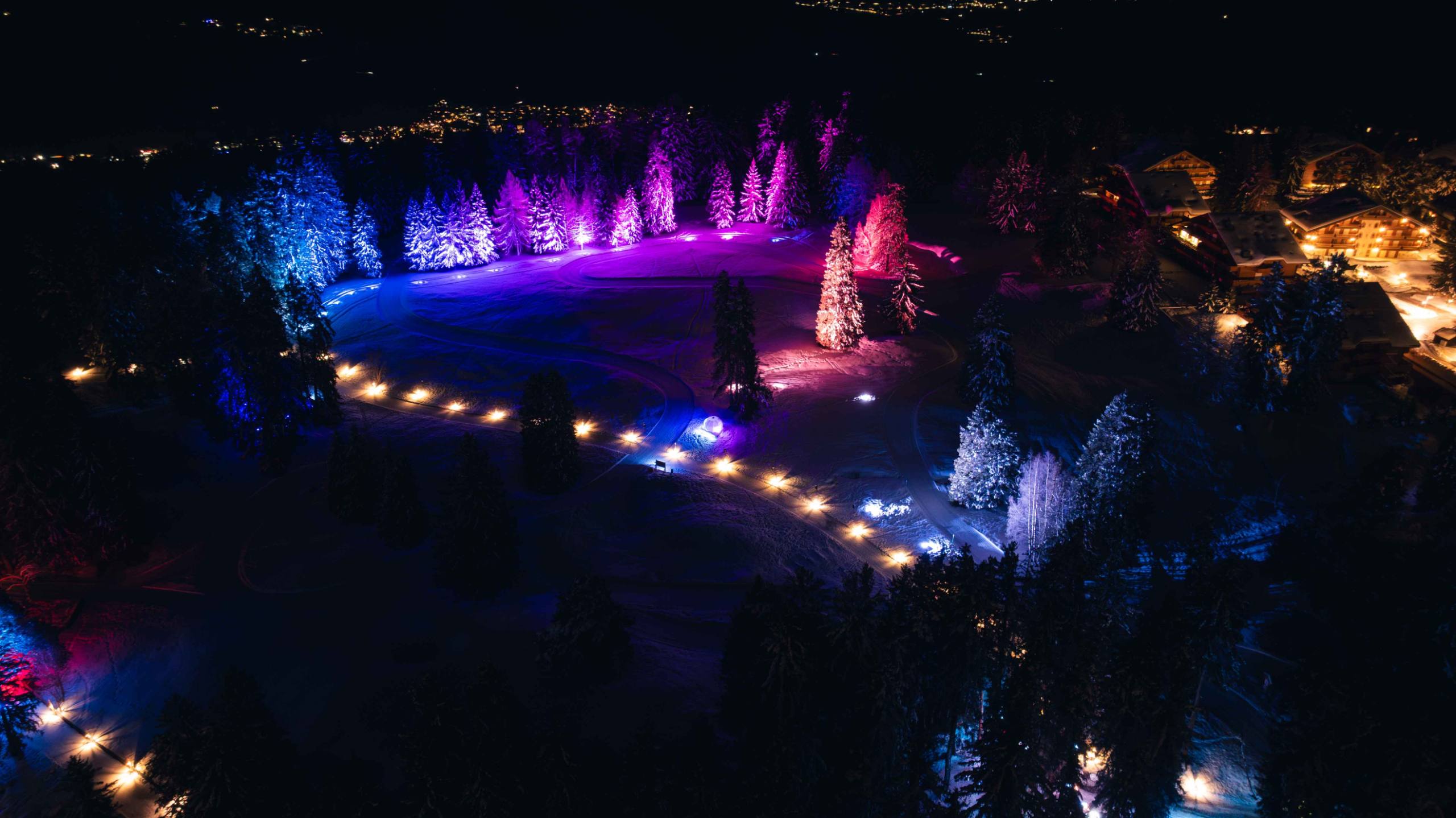 Le Chemin des Lanternes à Crans-Montana illuminé de nuit, vu de drone
