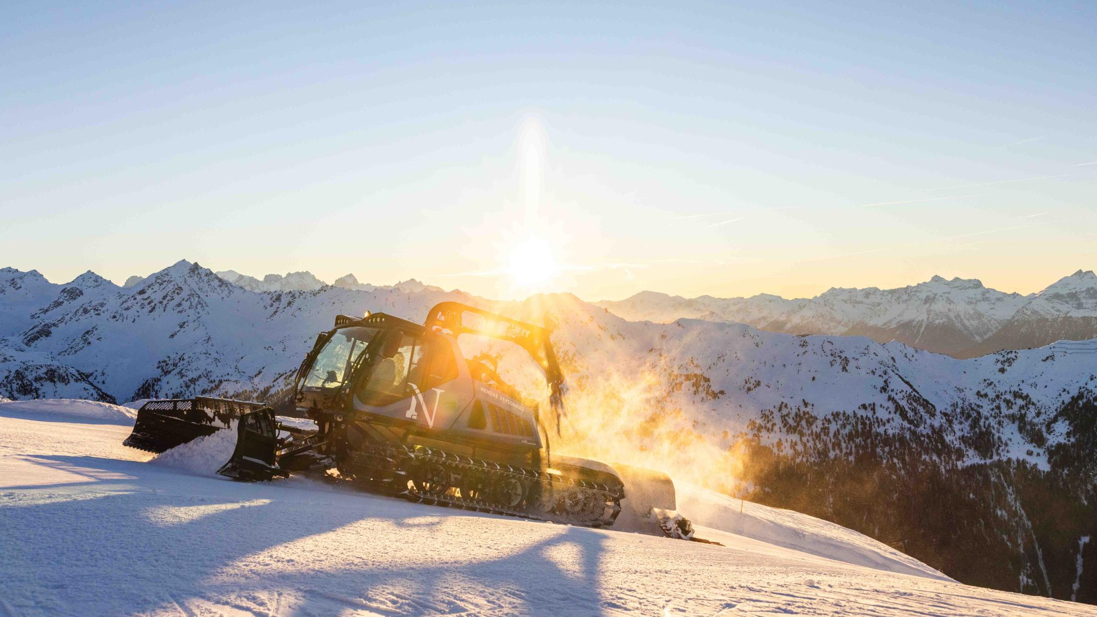 Dameuse Prinoth en action dans la neige, à contre-jour au soleil rasant
