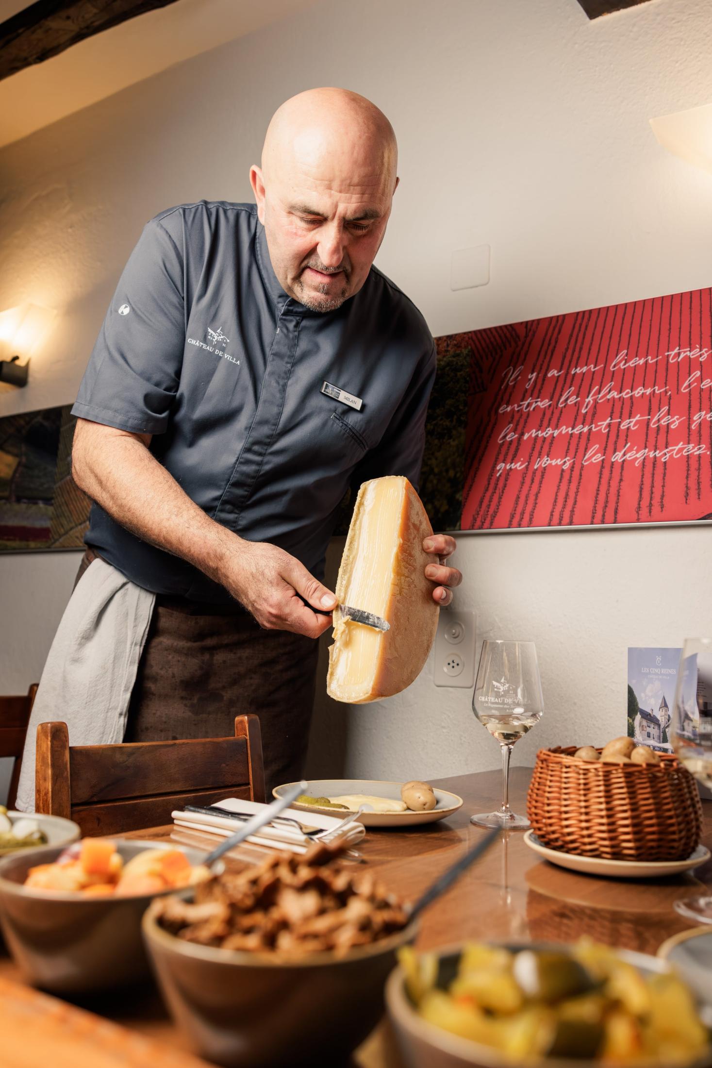 Racleur préparant la raclette devant un buffet