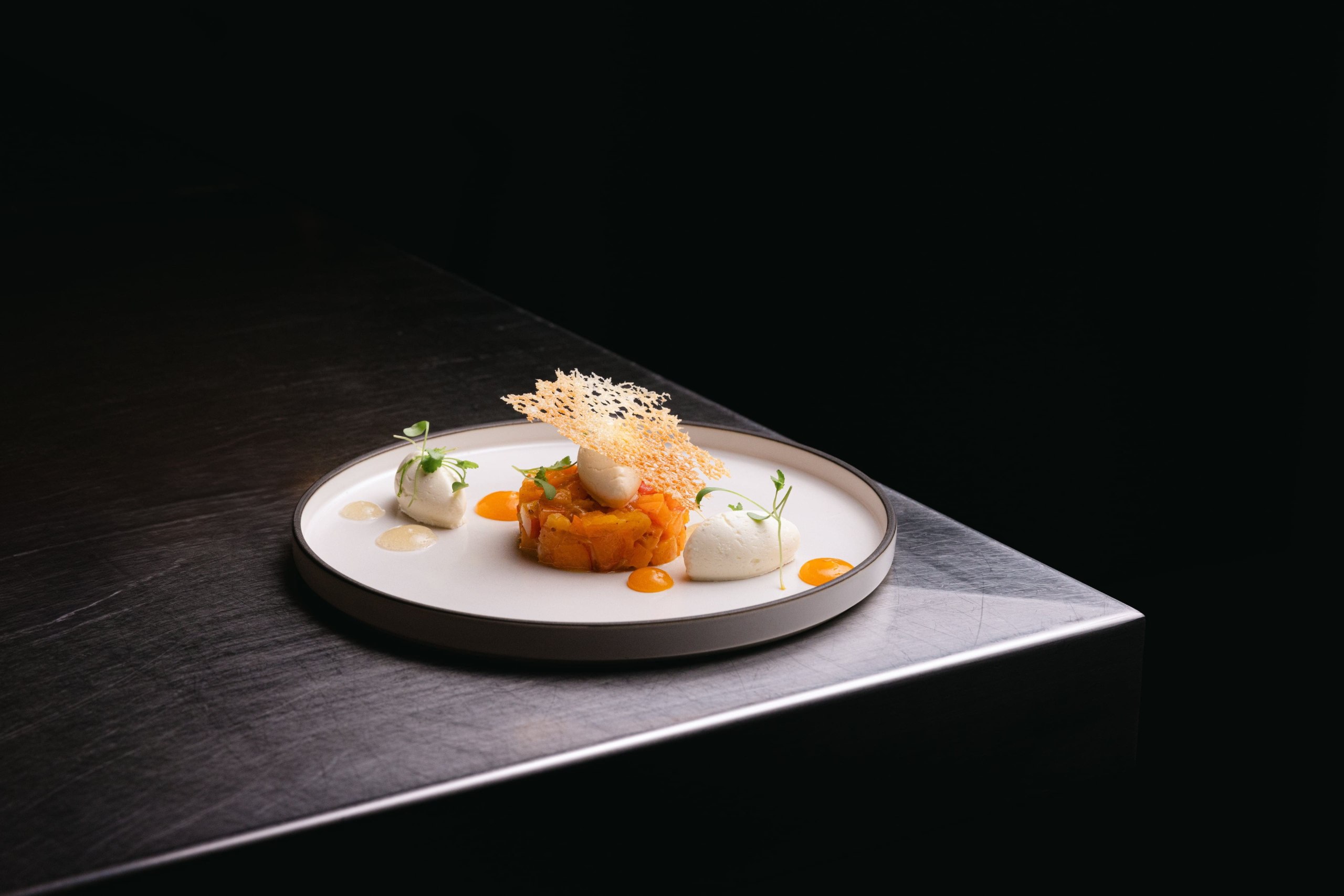 Assiette blanche dressée avec ses garnitures, sur fond noir