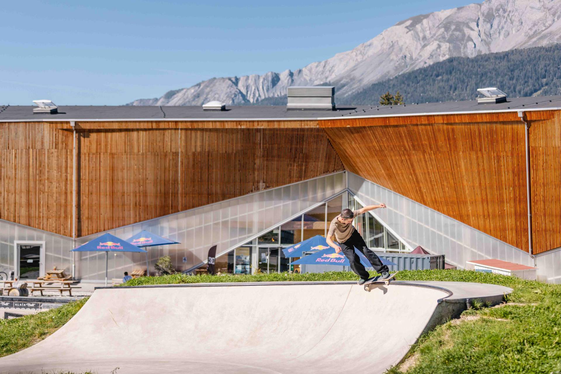 Skateur sur le bowl extérieur de l'Alaïa Chalet, montagnes en arrière-plan