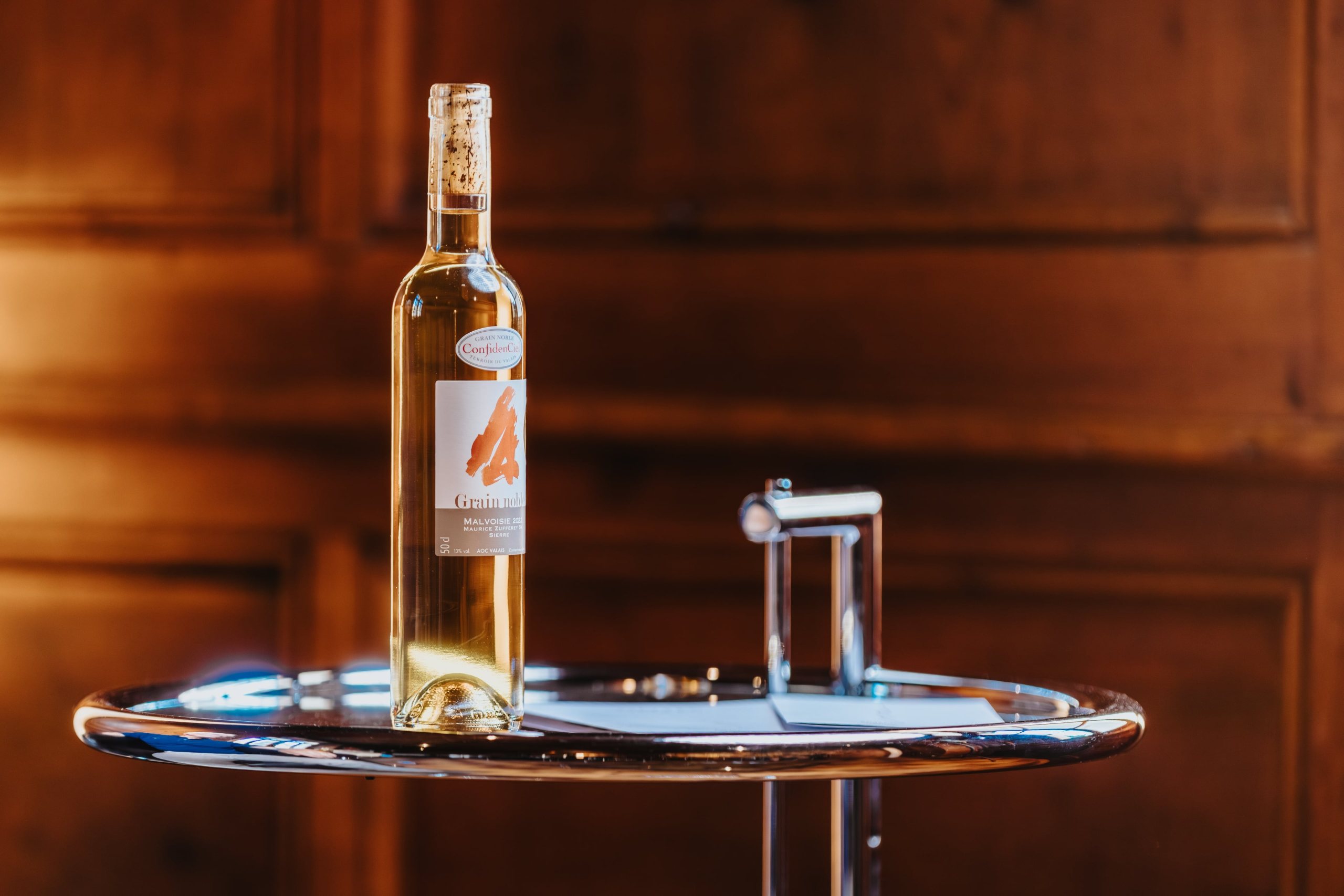 Bouteille de Grain Noble ConfidenCiel sur une table ronde, devant des boiseries