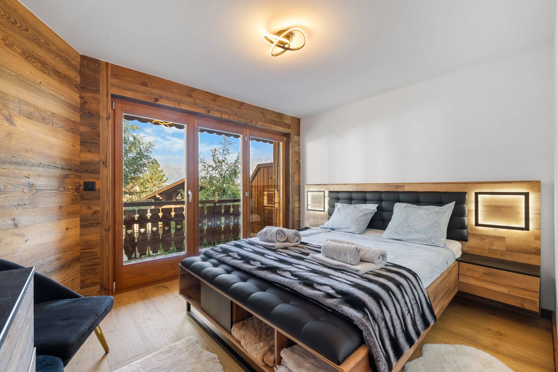 Chambre double avec boiseries et porte-fenêtre sur balcon, appartement Coeur des Alpes à Nendaz