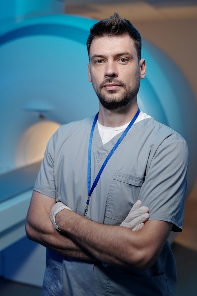 Medical professional standing in front of an MRI machine with arms crossed