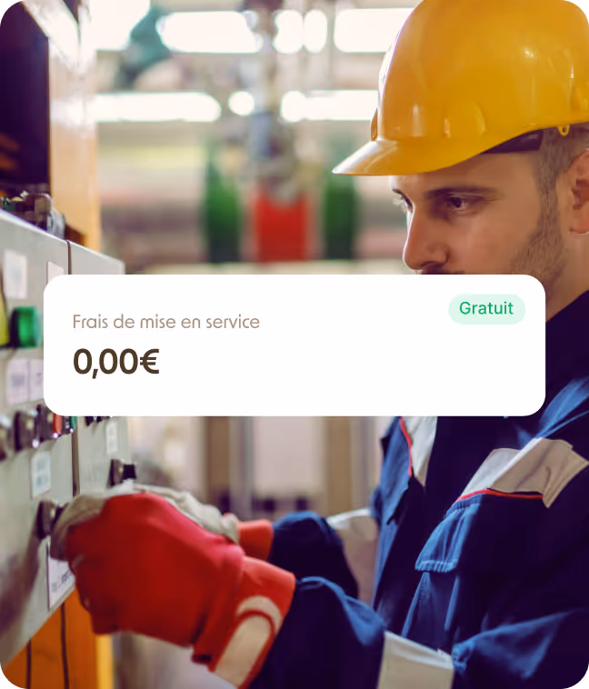 Un technicien en casque jaune et gants rouges ajustant un panneau de commande industriel avec une étiquette indiquant « Frais de mise en service 0,00€ Gratuit ».