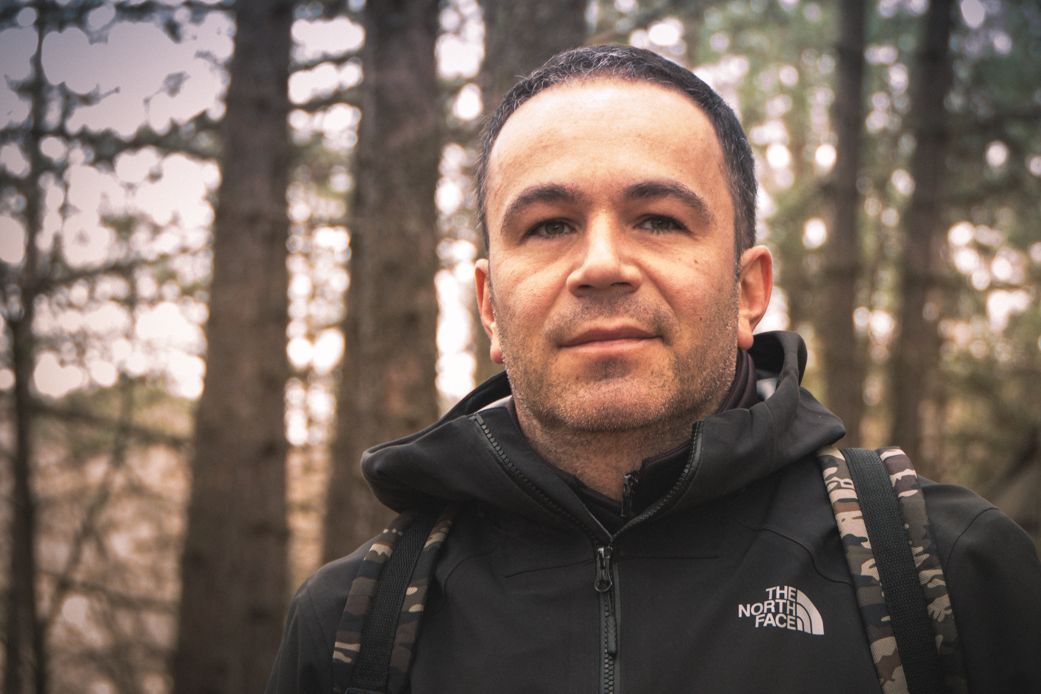 Author of the blog post. Image has been taken in wood. Man has black short hair, black jacket and military backpack