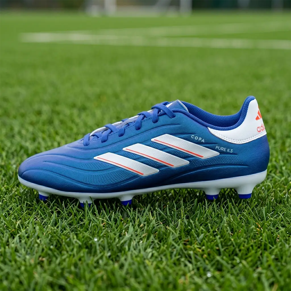 Adidas Copa Pure II.3 FG Junior football boots. Royal blue kids' leather football shoe shown in a detailed profile view on a grass surface. Premium comfort and traction featured on the Junior Striker Top 10 list