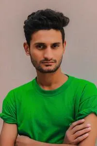 Photo of a candidate. Young man with dark skin, bright green t-shirt and crossed arms.