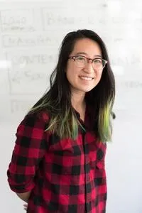 Photo of a candidate. Woman in glasses, smiling and wearing red shirt.