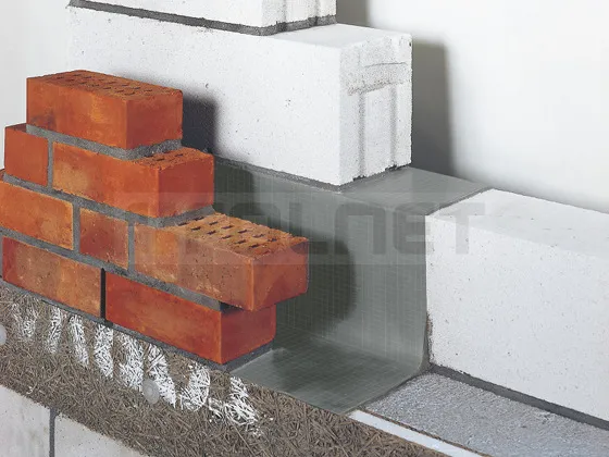 A brick wall with a brick laying on the ground.
