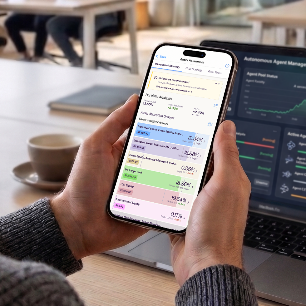 A man in a startup environment looking at the Enrich app on his phone. The app is displaying the Investment Strategy page for a Goal. At the top, he can see a yellow rebalance alert, followed by an overall portfolio analysis, and finally their investment strategy for that goal.
