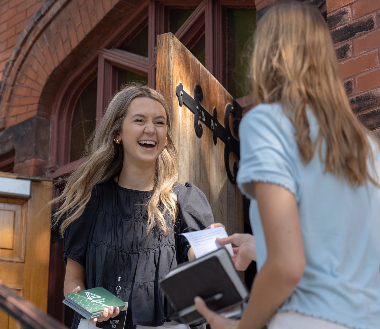 Women welcoming a first-time visitor at the front doors of Ambassador Church in Milwaukee