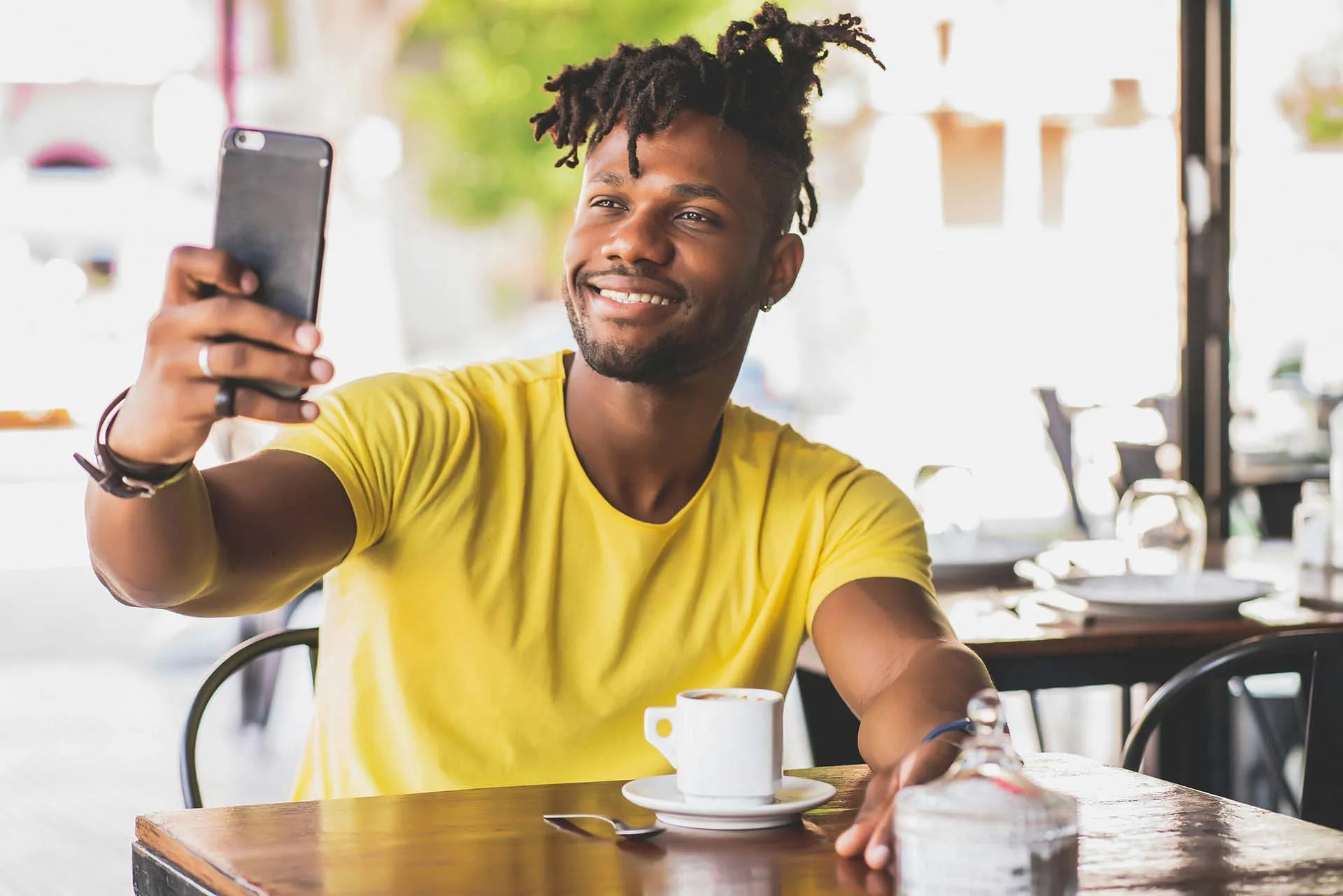 Man having cofee and smiling at phone