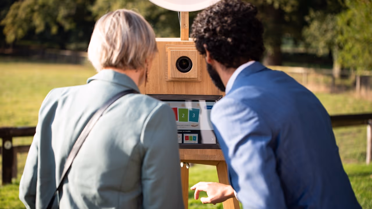Location photobooth Angers couple utilisant borne photo bois extérieur